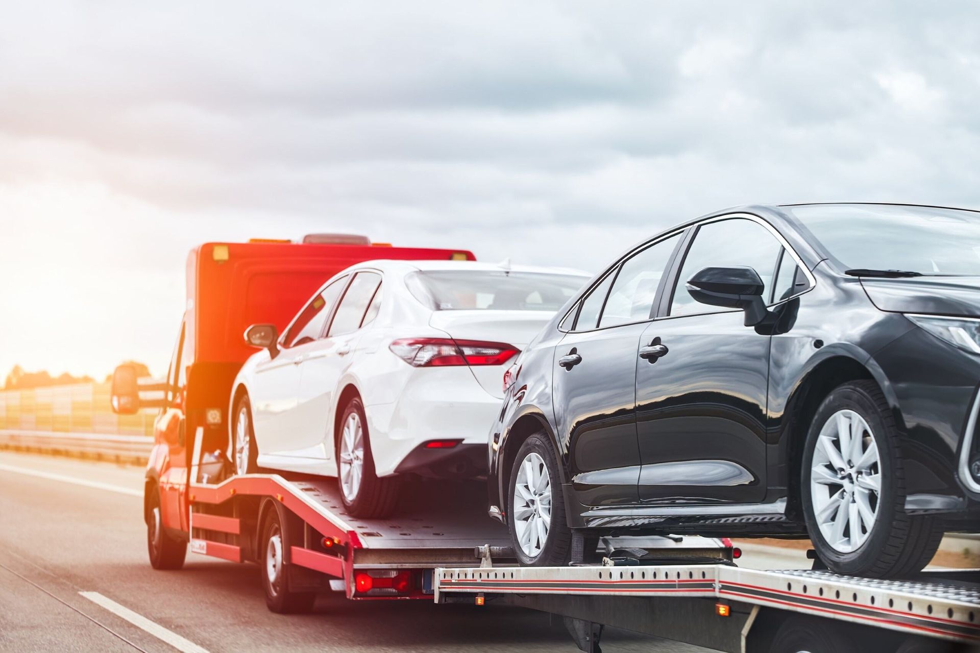 Two Cars Are Being Towed by a Tow Truck on a Highway — Hervey Bay Tilt Tray Hire In Bundaberg, QLD