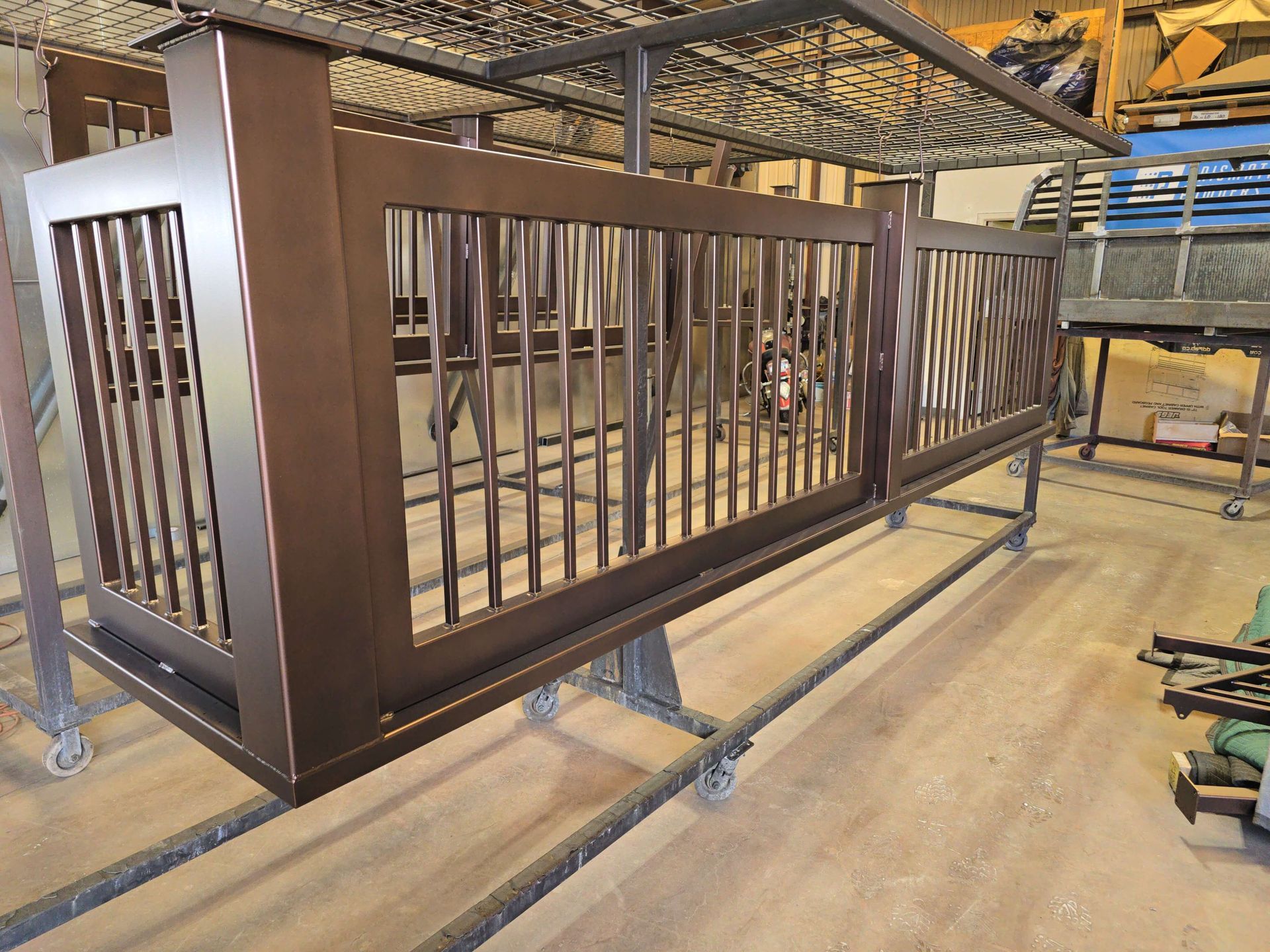 Brown metal railing panel on a workshop floor, with vertical bars and a rectangular frame.