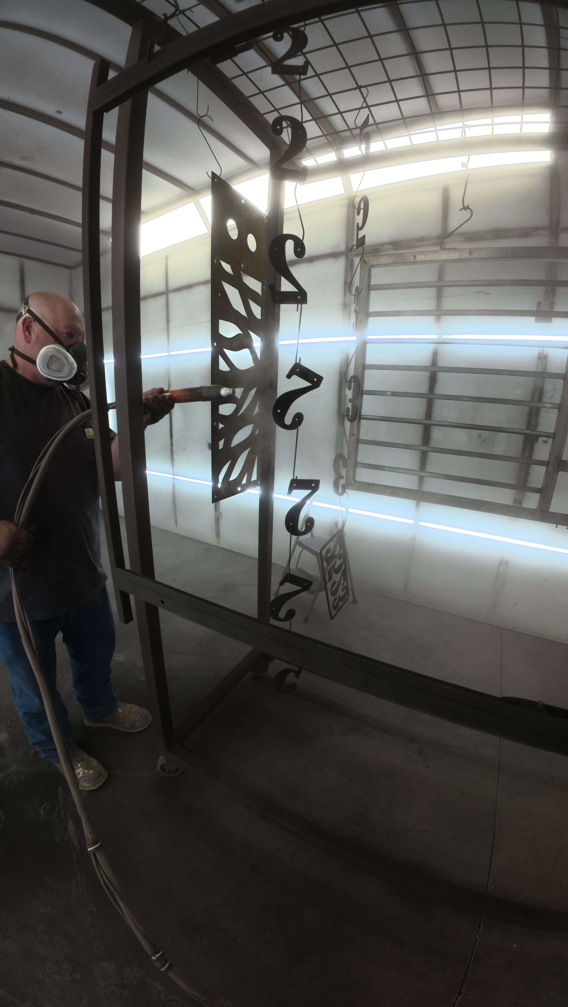 Glass wall with decorative black lettering, reflecting a person standing beside it in a covered area