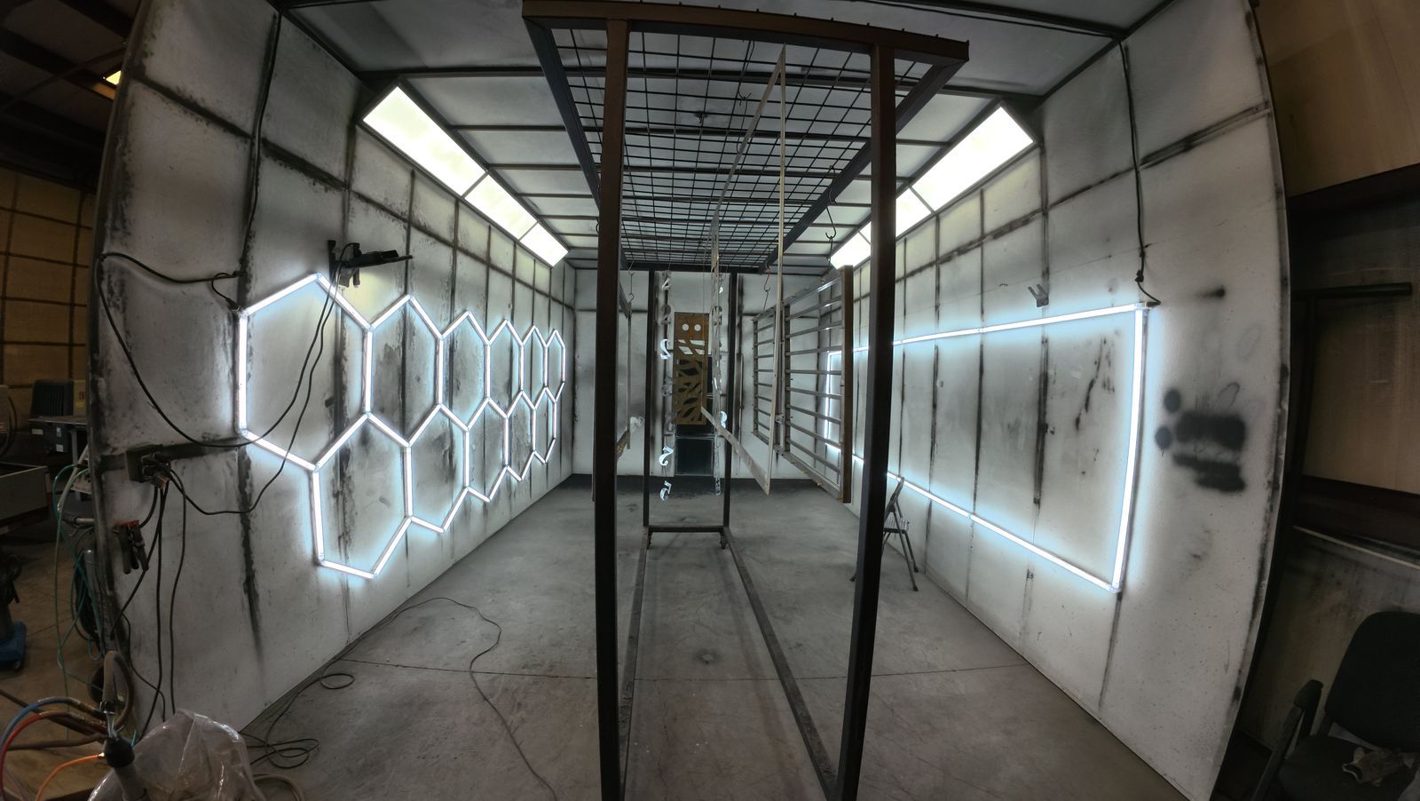 Long industrial corridor with glowing hexagonal wall lights and a central metal frame, seen in perspective