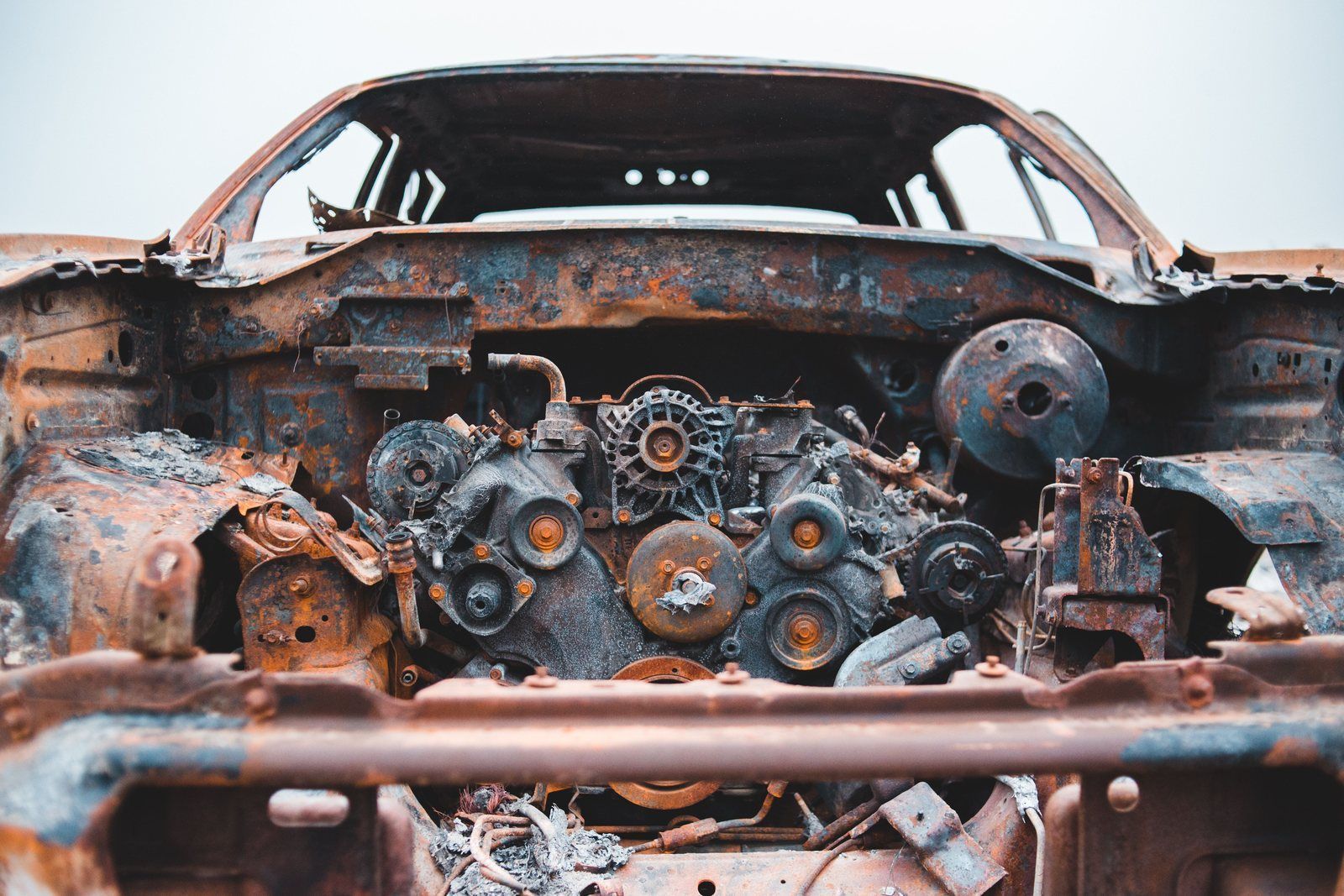 Heavily rusted car body and engine bay with scaled, pitted metal and corroded parts
