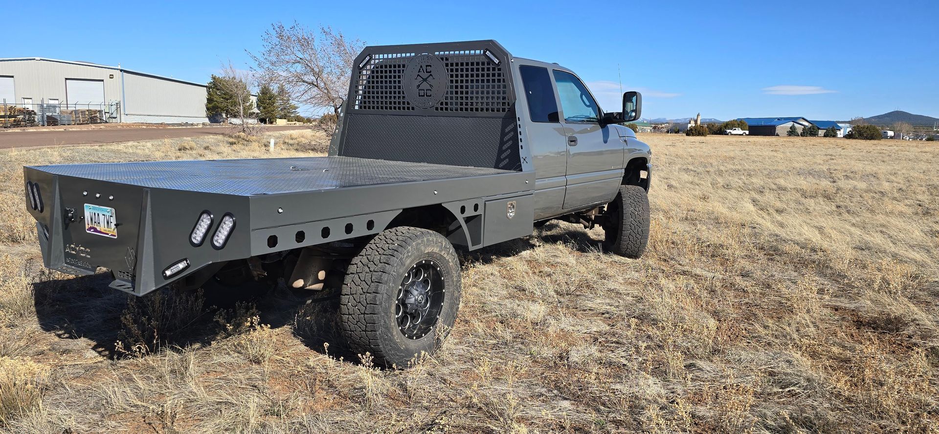 Black flatbed pickup truck parked in a dry field under a blue sky