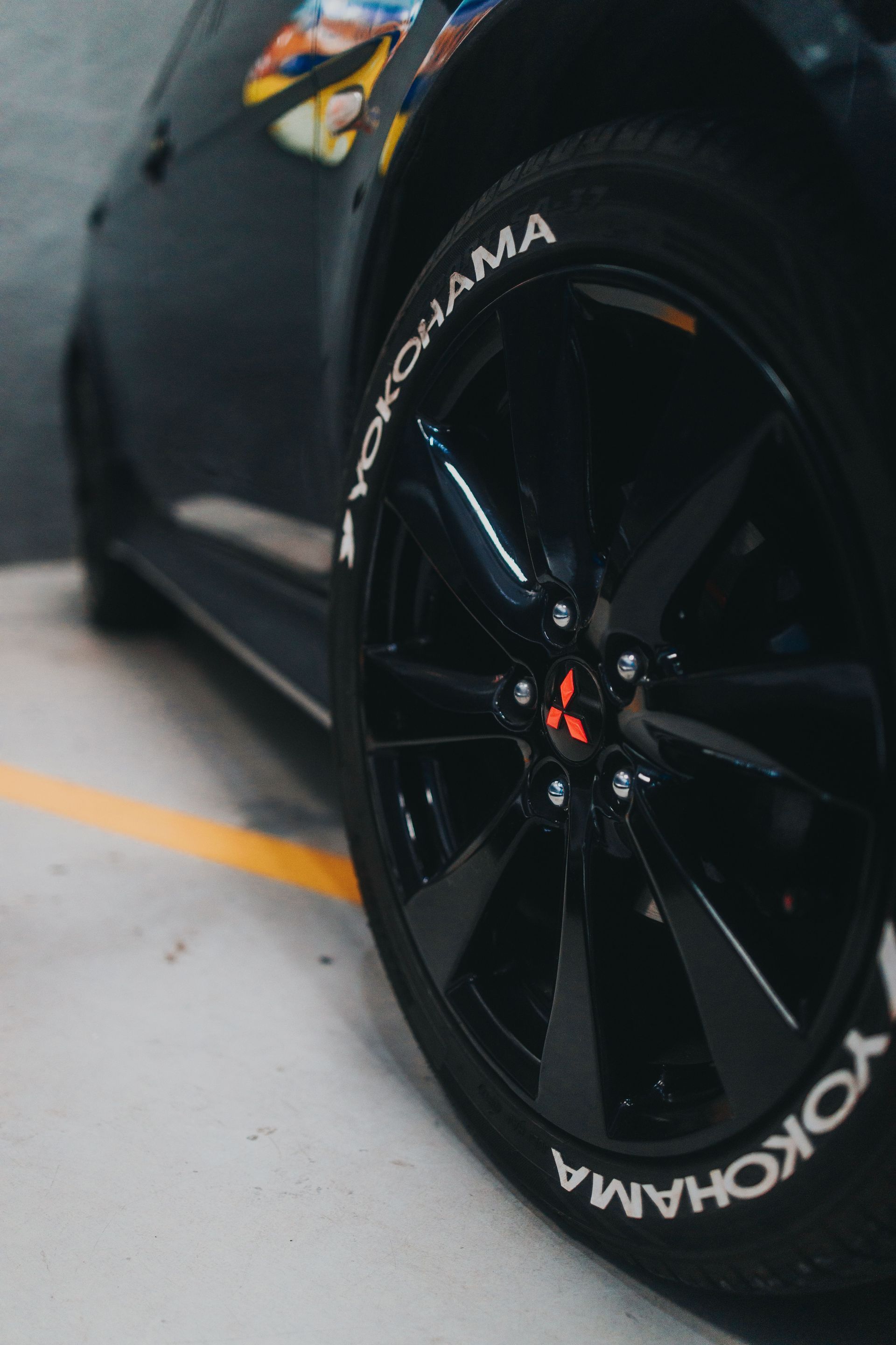Powder Coated Black car wheel with Yokohama tire on a garage floor