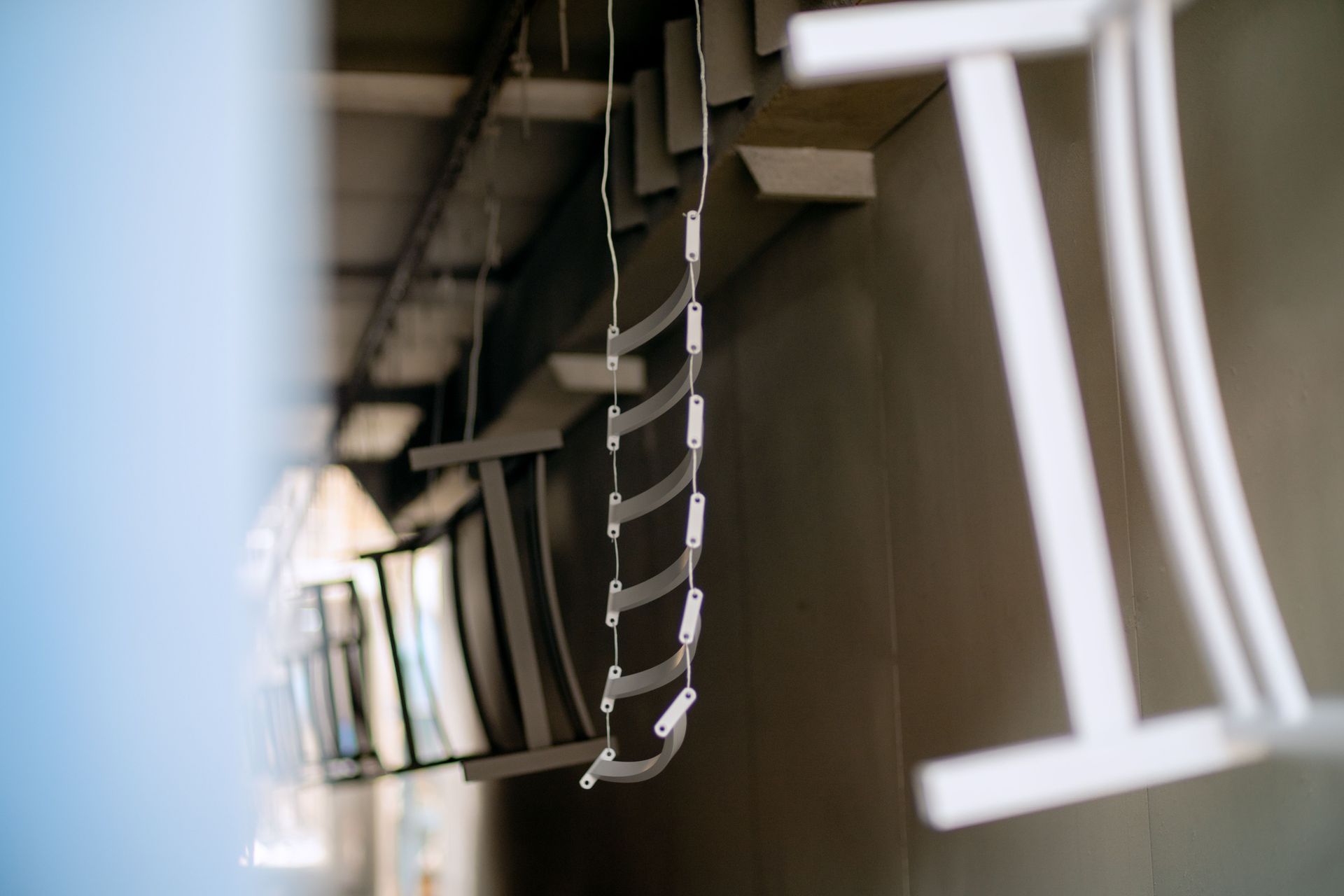 Close-up of a hanging metal chain with blurred white cables in an industrial setting