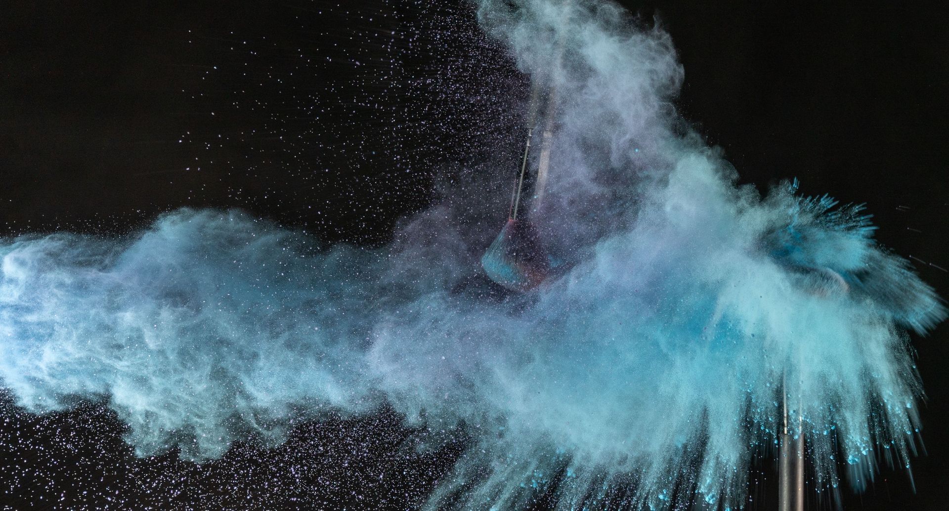 Blue powder cloud bursting against a black background