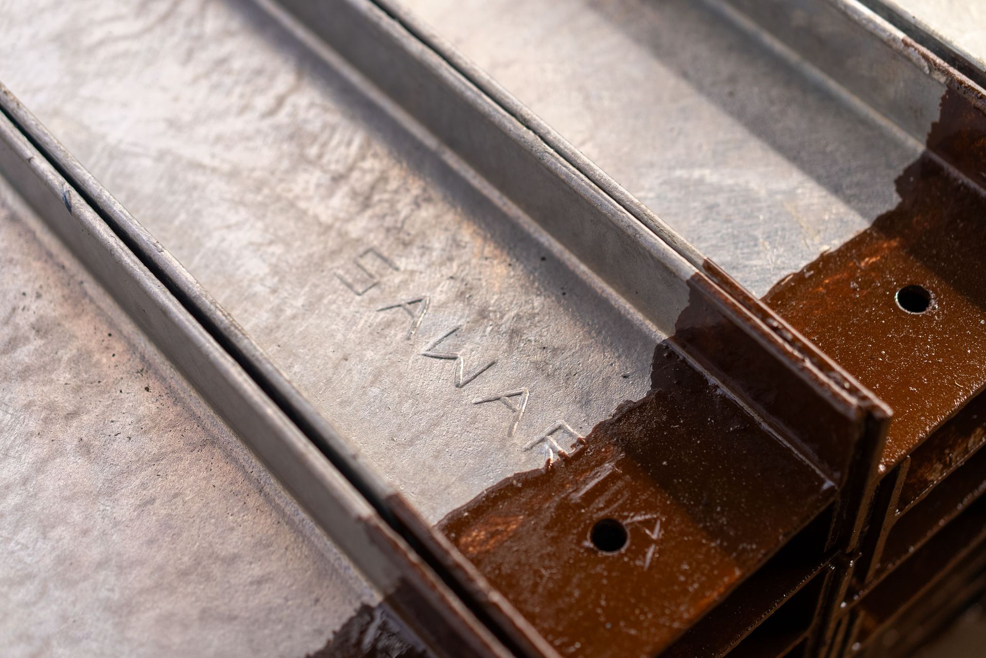 Close-up of metal roofing panels with rusted brackets and fasteners