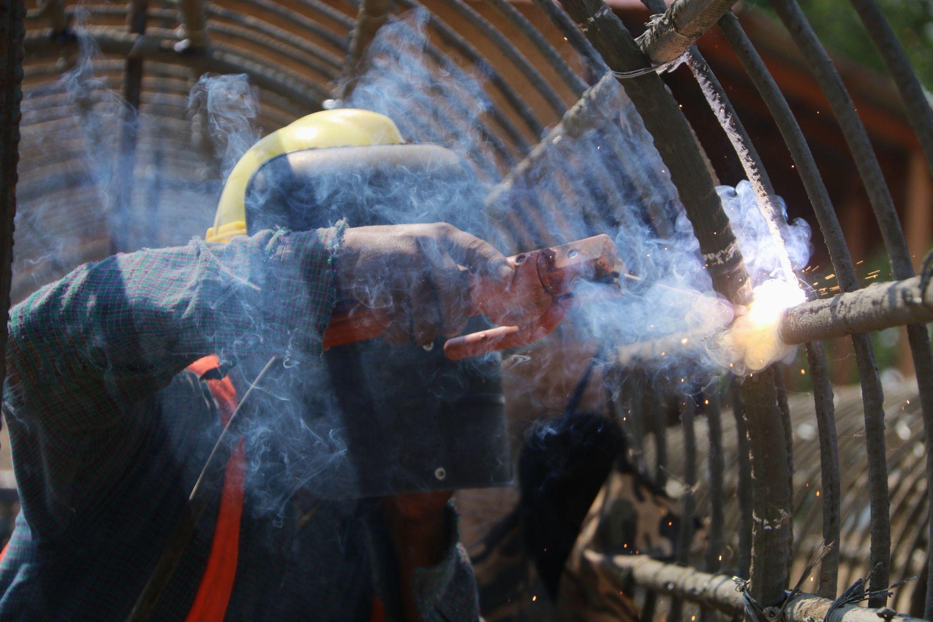 Person in a yellow helmet operating a water spray hose inside a tunnel-like structure