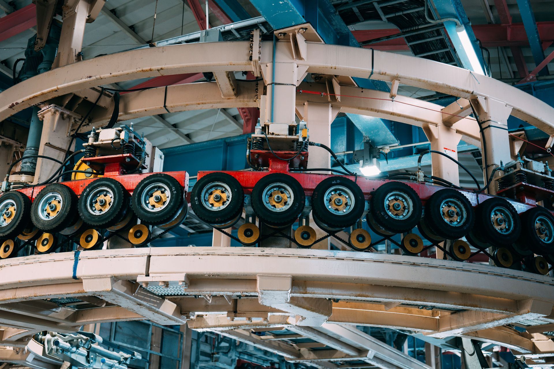 A roller coaster train curves through an indoor track with red seats and yellow wheels.