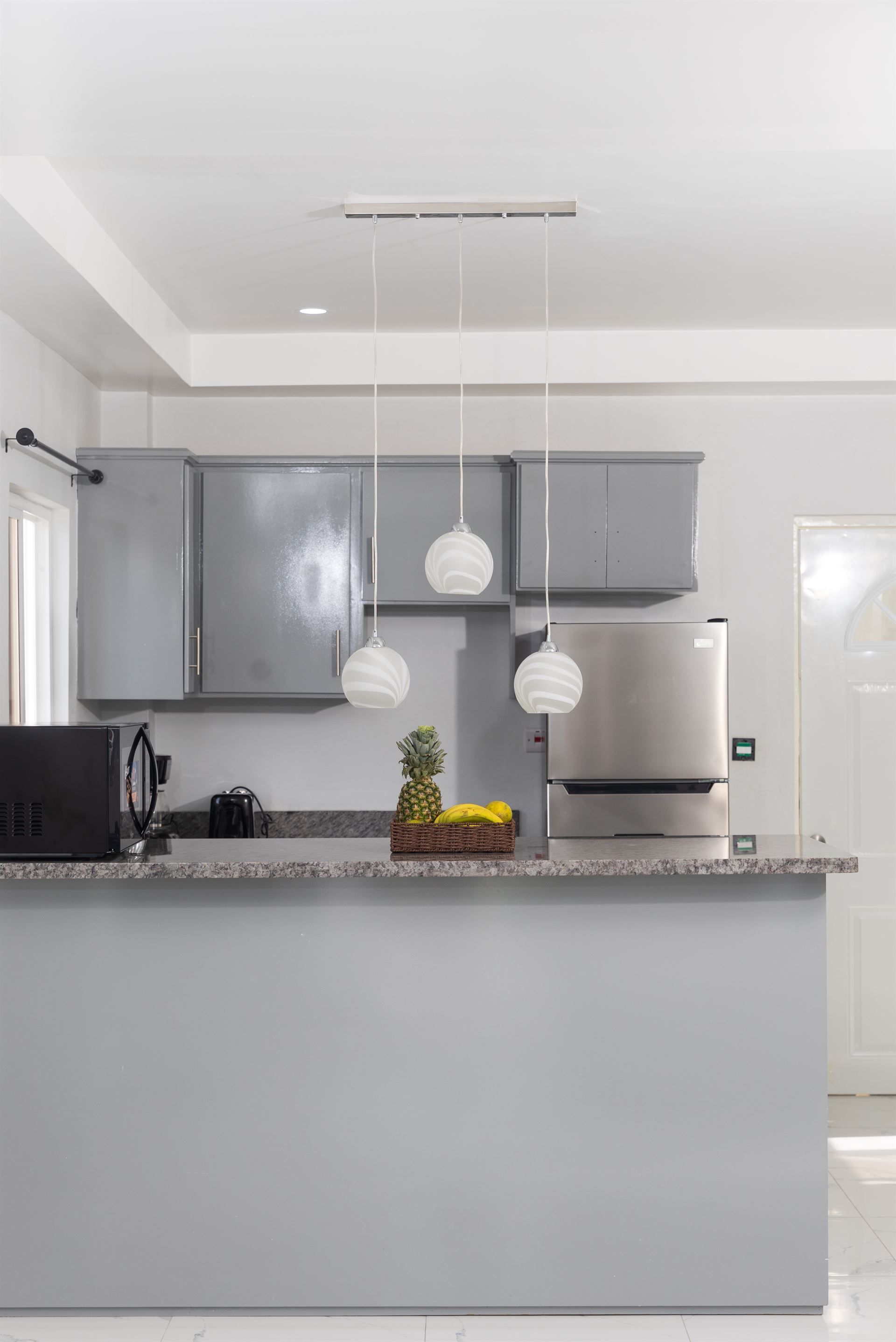 A kitchen with gray cabinets , granite counter tops , stainless steel appliances and a refrigerator.
