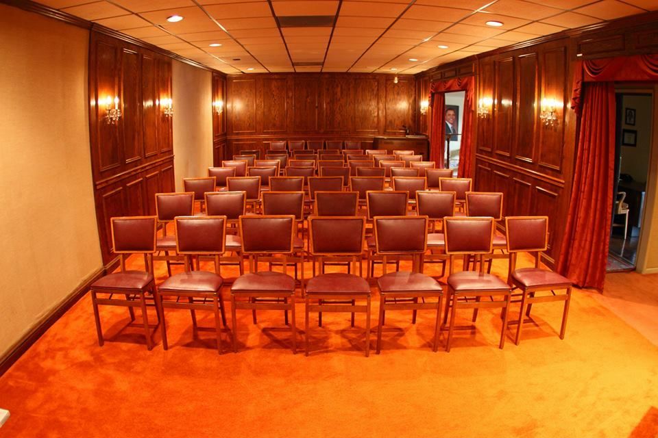 Empty conference room with rows of wooden chairs on an orange carpet and wood-paneled walls