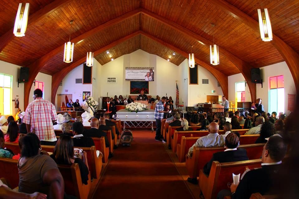 Church congregation seated in a sanctuary with a high wooden ceiling and altar at the front