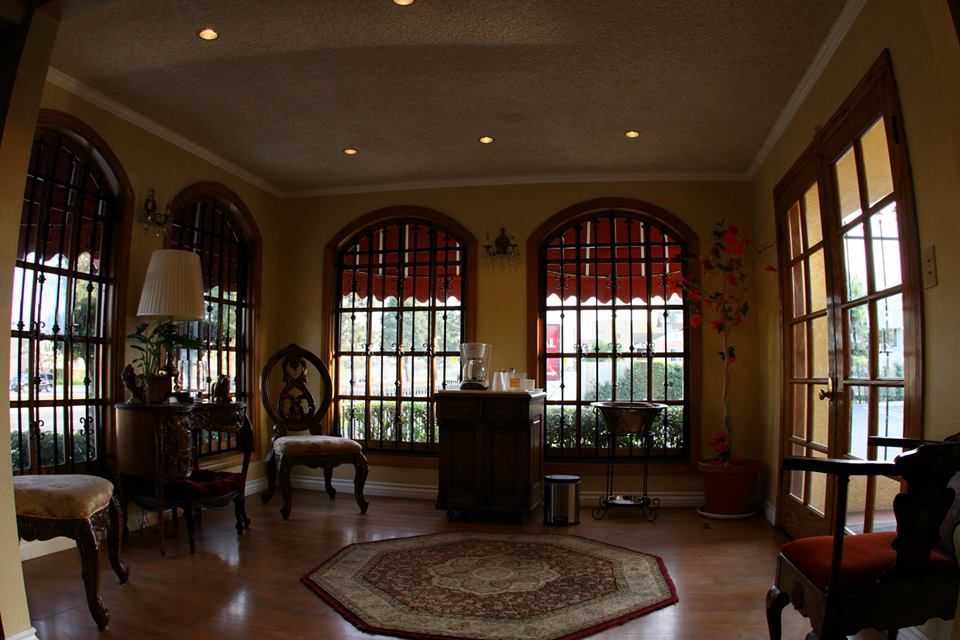 Elegant living room with arched windows, red drapes, chairs, and a round rug