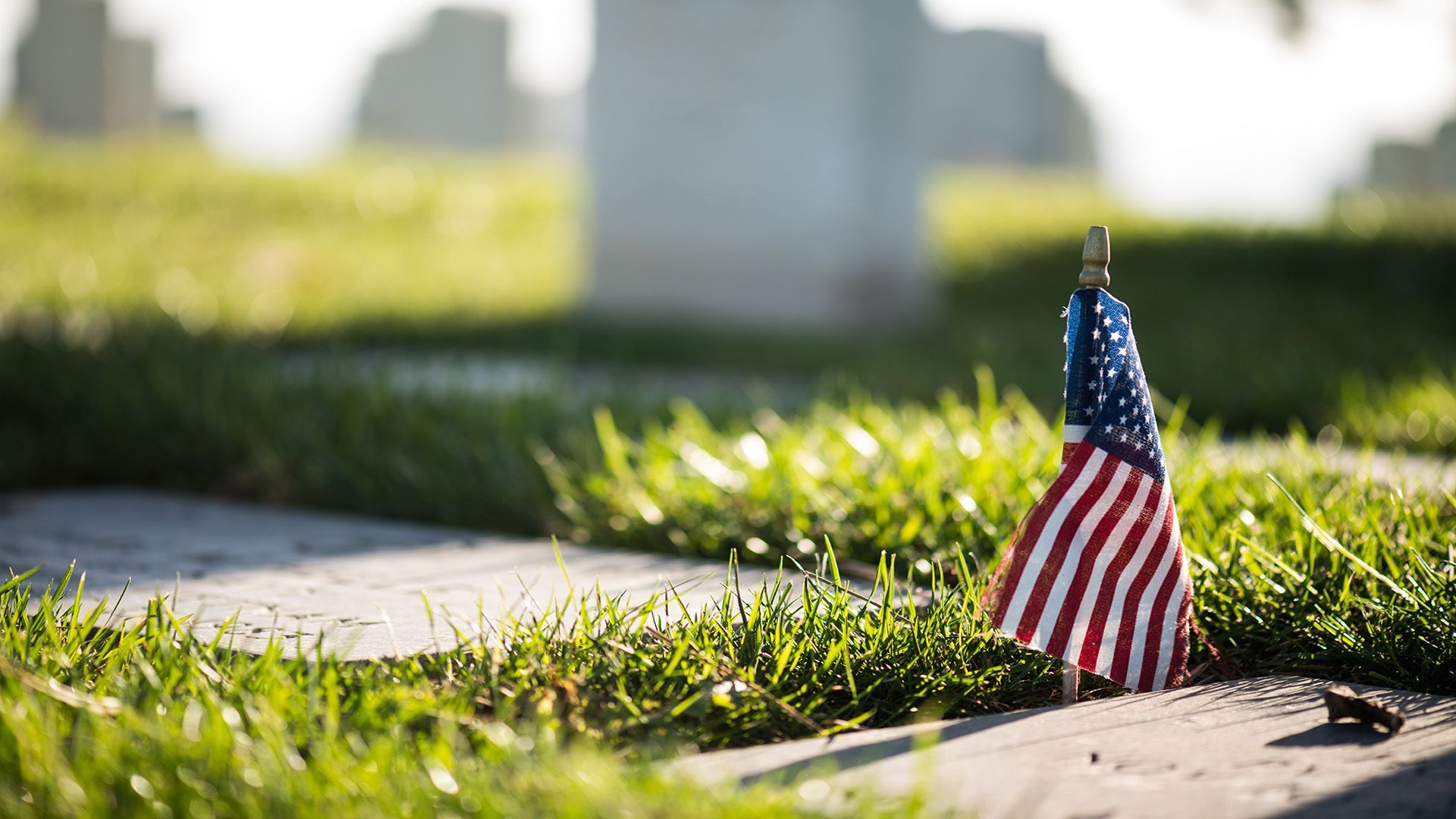 A man in a military uniform is holding an american flag in his hands.
