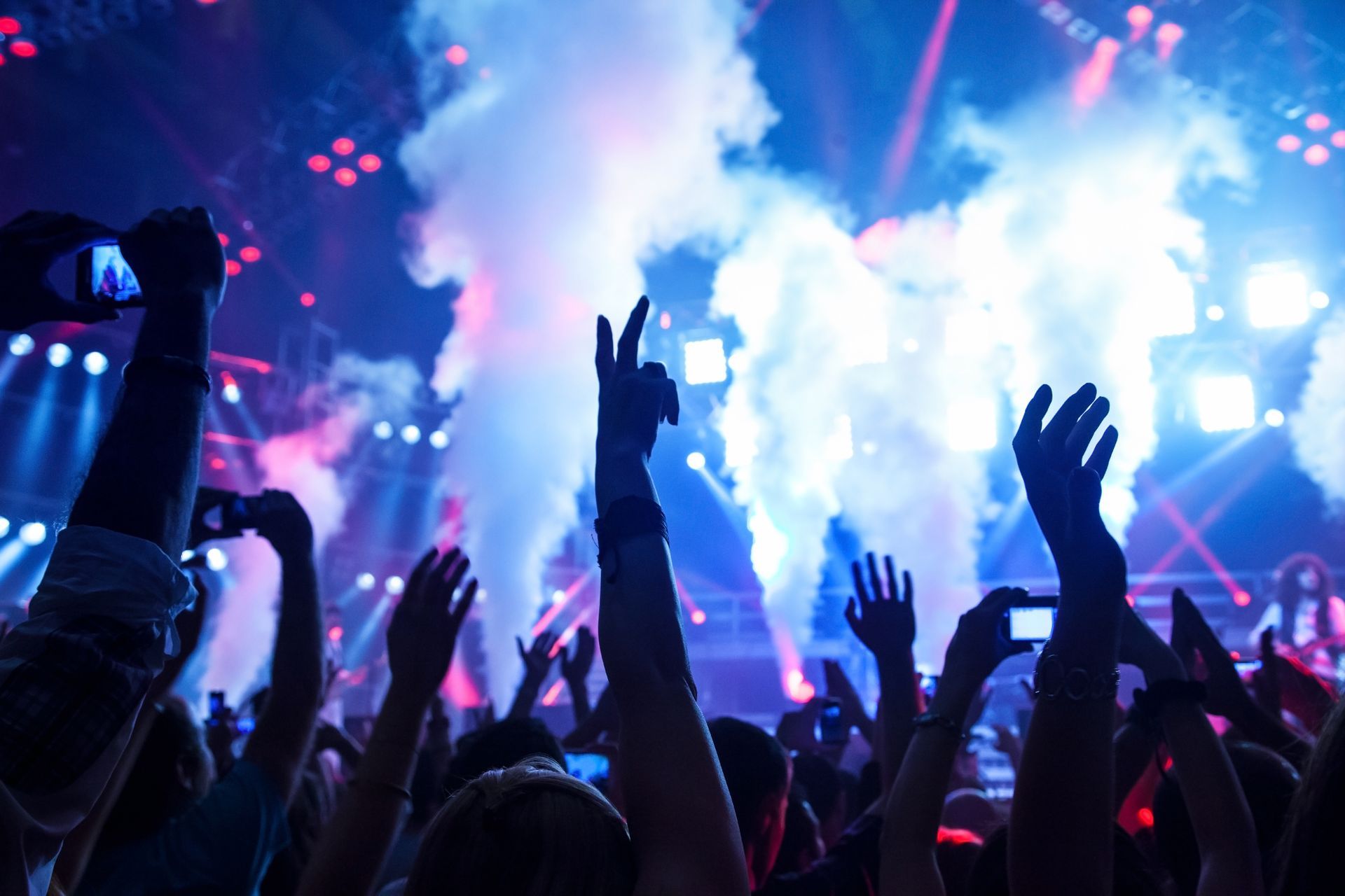 A crowd of people at a concert with their hands in the air.