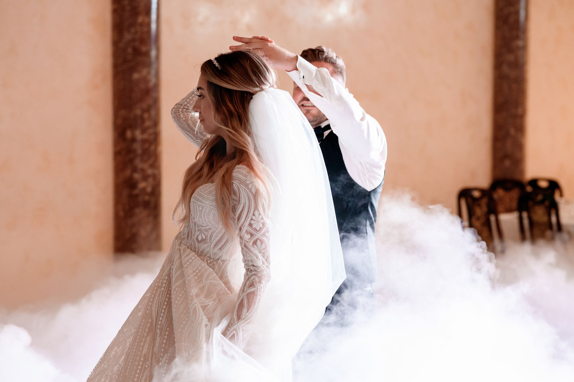 A bride and groom are dancing in the smoke at their wedding reception.