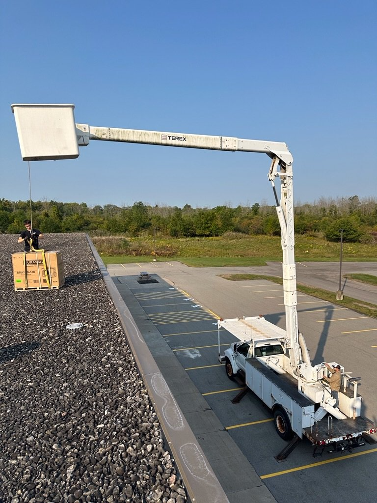 A white truck with a crane on the back is parked in a parking lot.