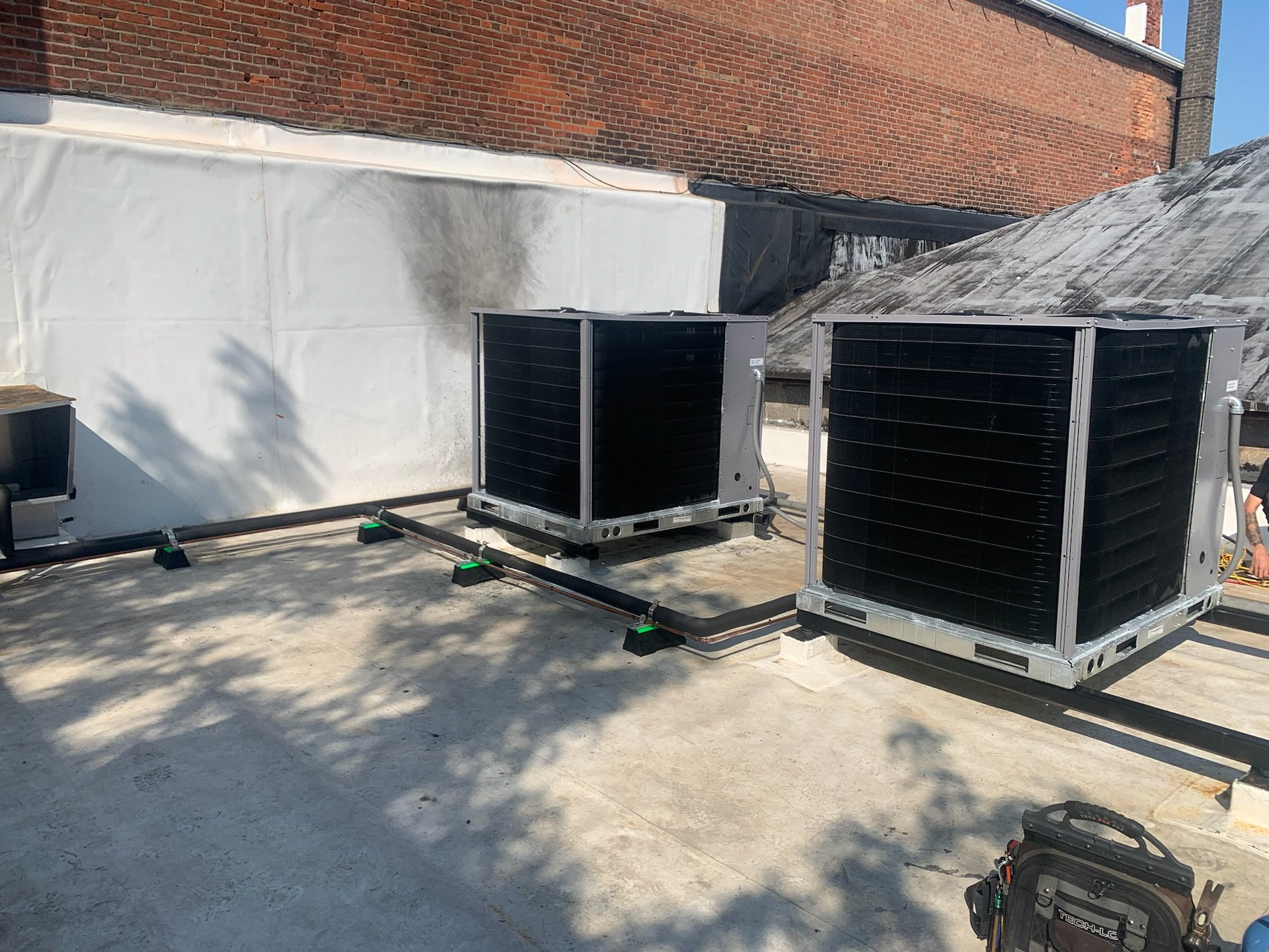 Two air conditioners are sitting on the roof of a building.