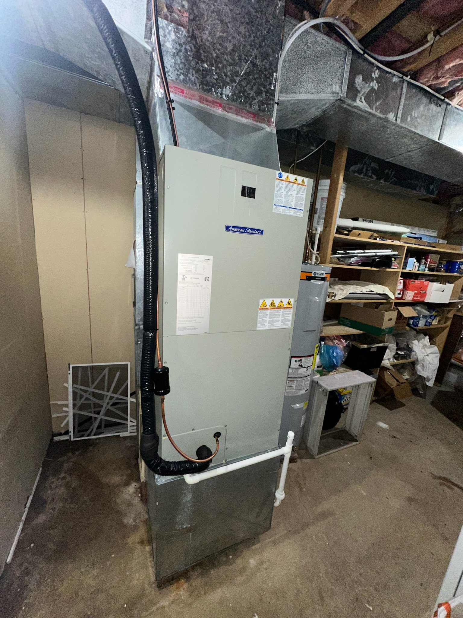 A large air conditioner is sitting in a basement next to a wall.