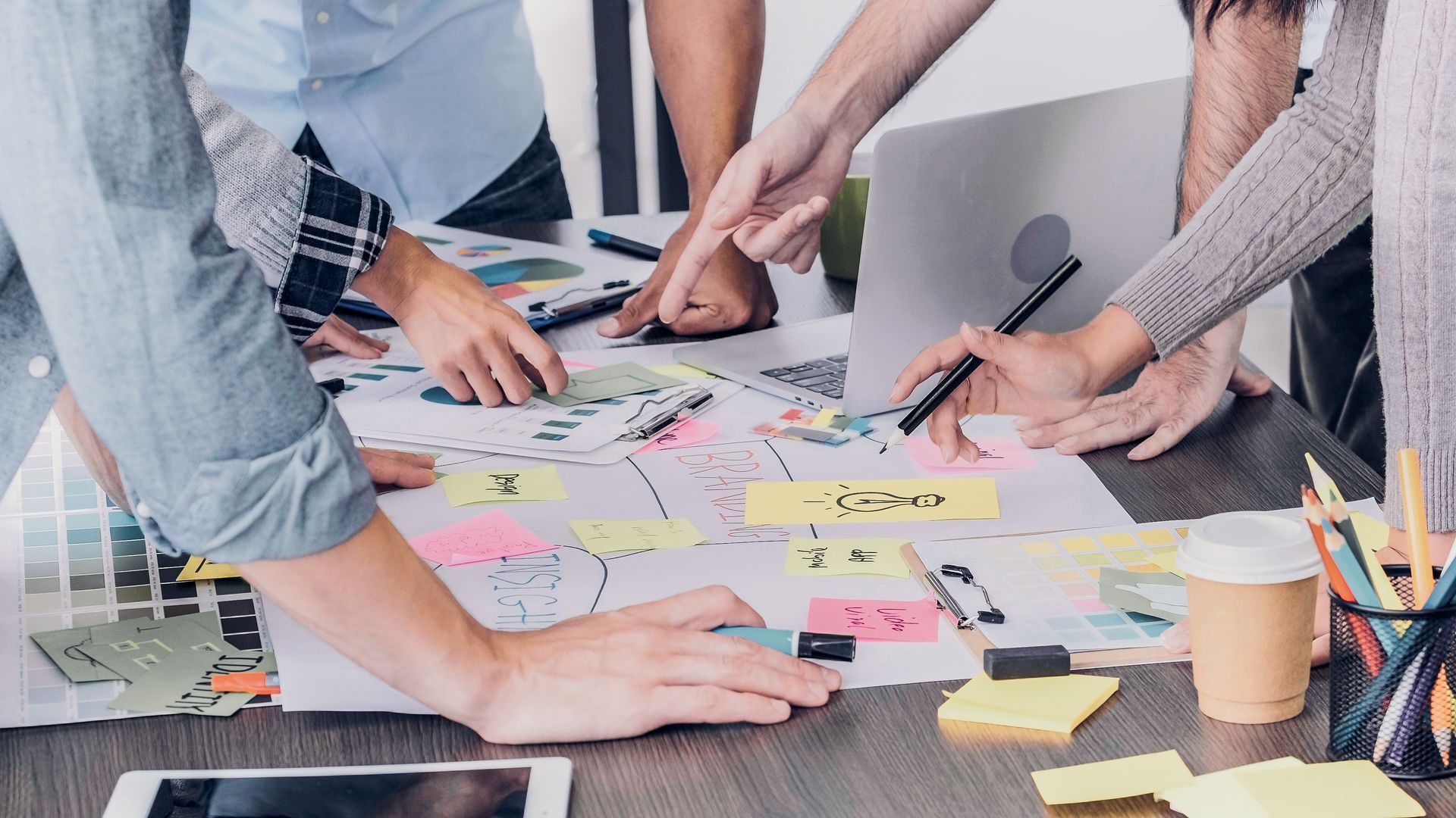 Une équipe collabore autour d'une table, pointant du doigt des documents