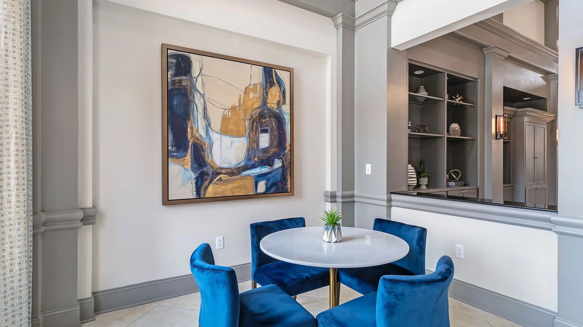 A clubhouse with a table and chairs, and a painting on the wall at The Carlyle at Godley Station.