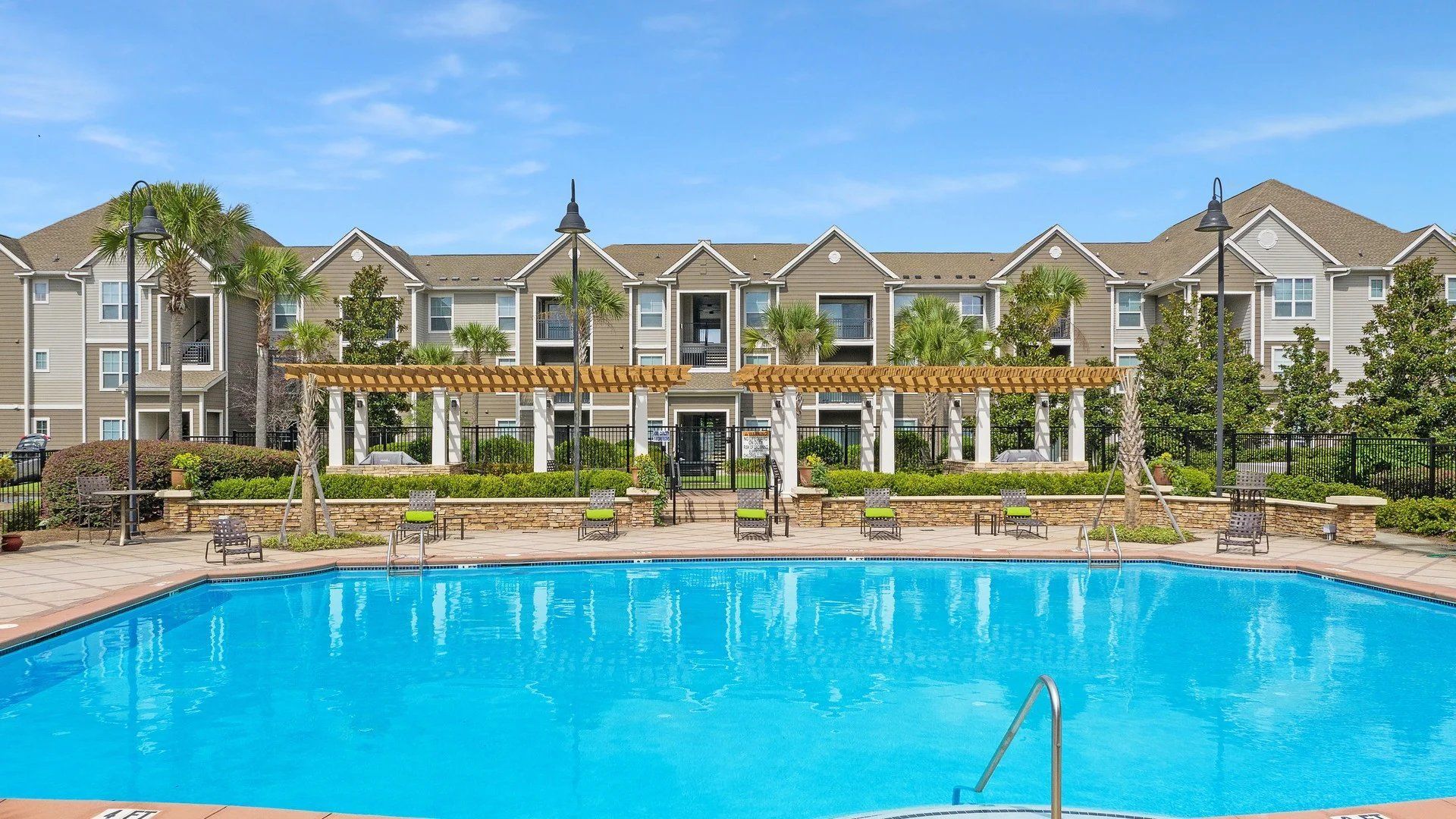 A large swimming pool in front of a large apartment building at The Carlyle at Godley Station. Pooler apartments for rent.
