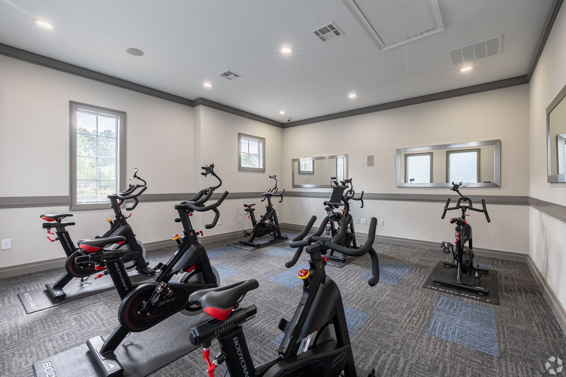 Indoor fitness room with several stationary bikes and gray walls at The Carlyle at Godley Station apartments in Pooler, GA.
