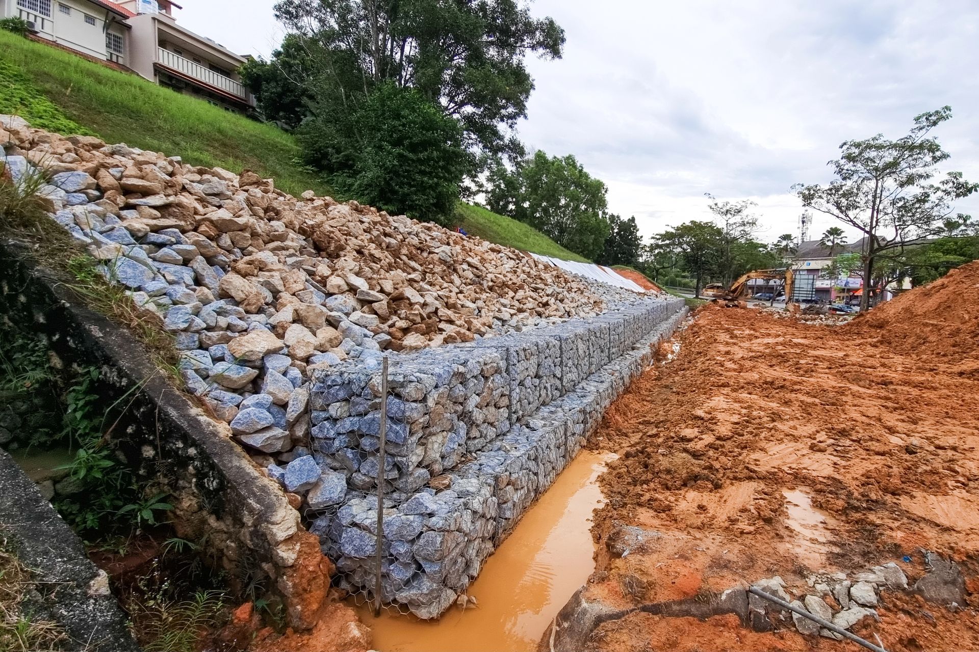 Costruzione di muri di contenimento in gabbioni; pendio, rocce e fango.