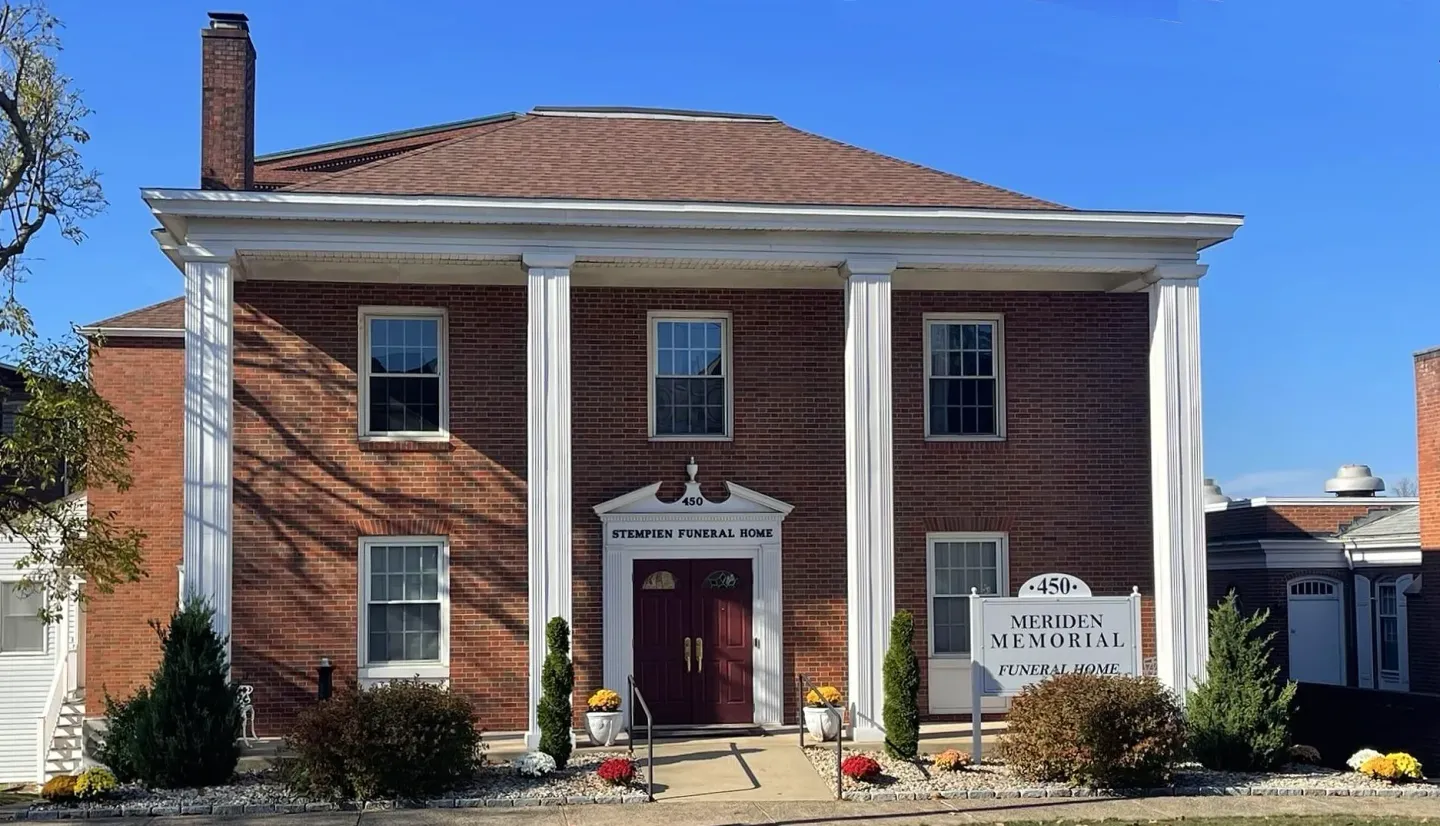 Brick building with a red door and white trim, decorated with signs and holiday decor under a blue sky
