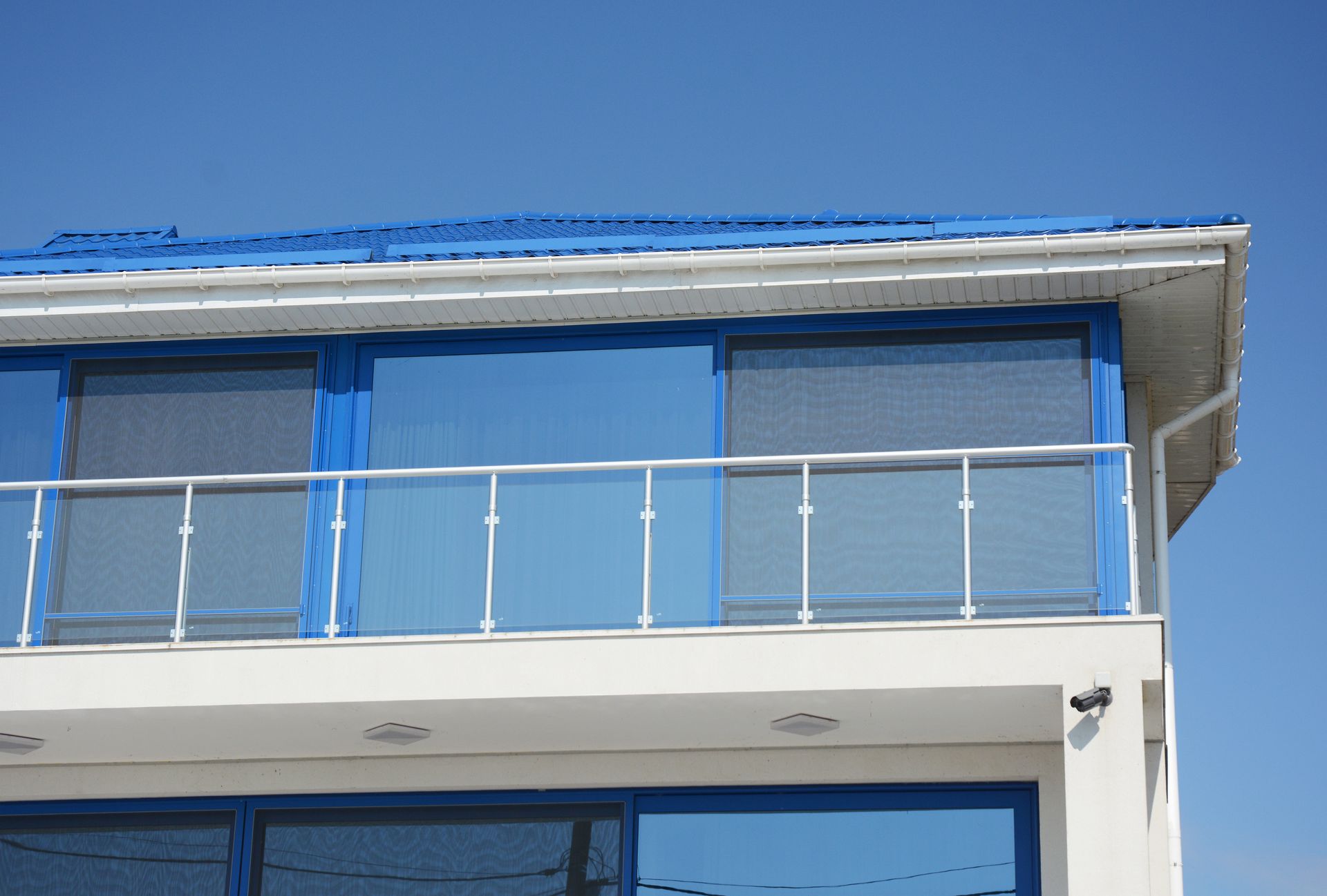 Modern building facade with blue windows and a glass balcony railing