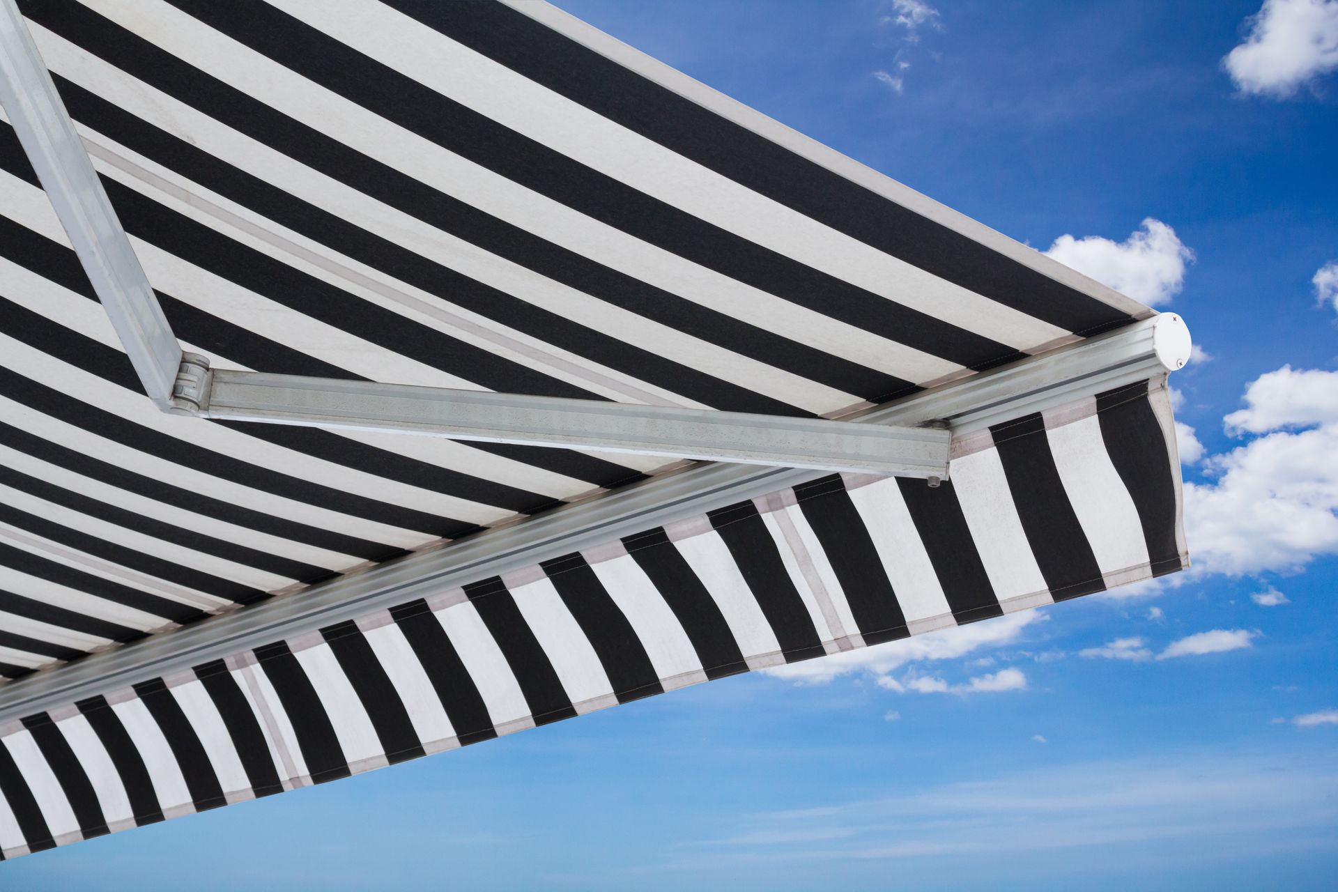 Black-and-white striped awning against a blue sky with clouds