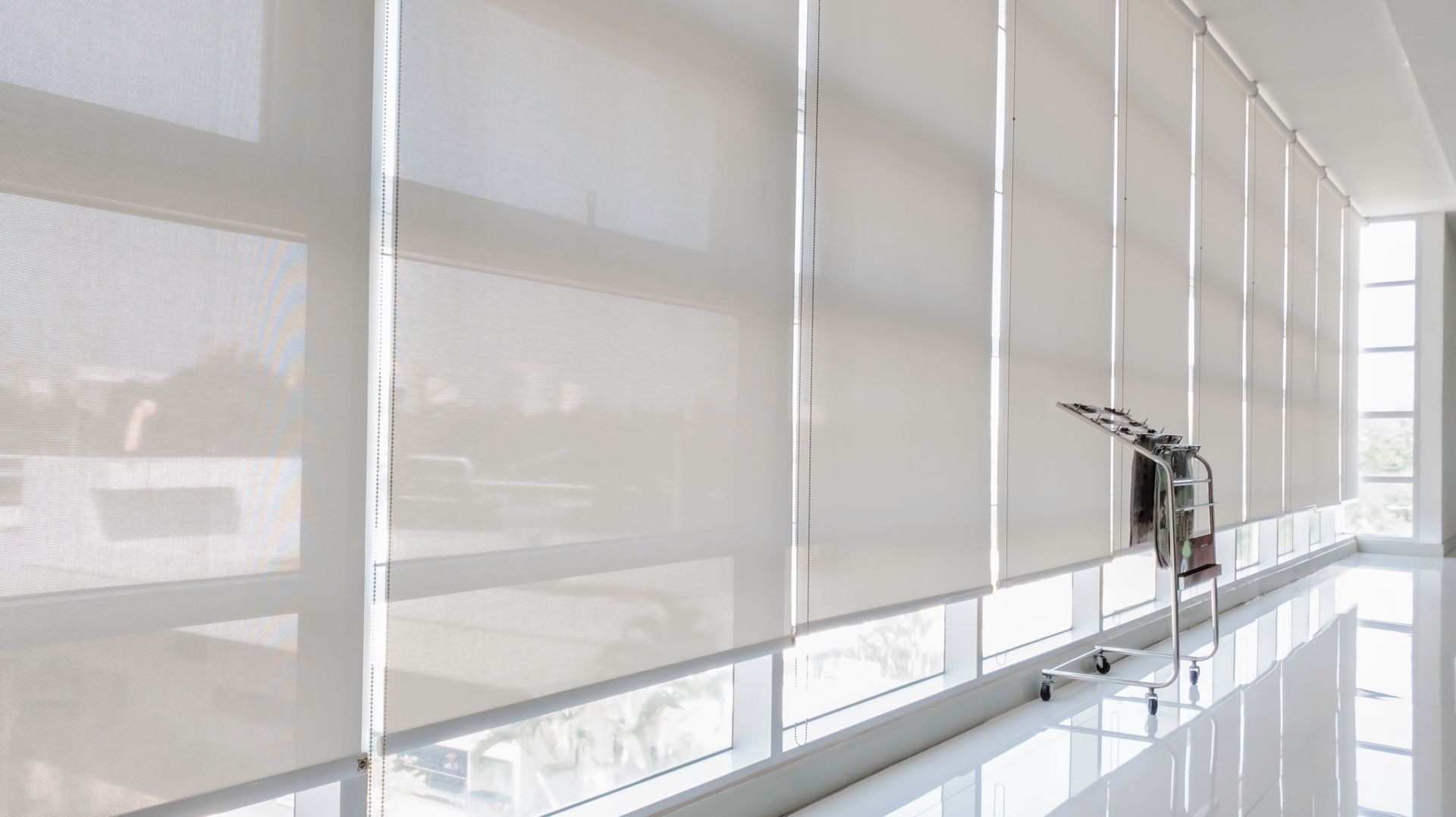 Bright office with white window blinds and a chrome faucet by a glossy counter
