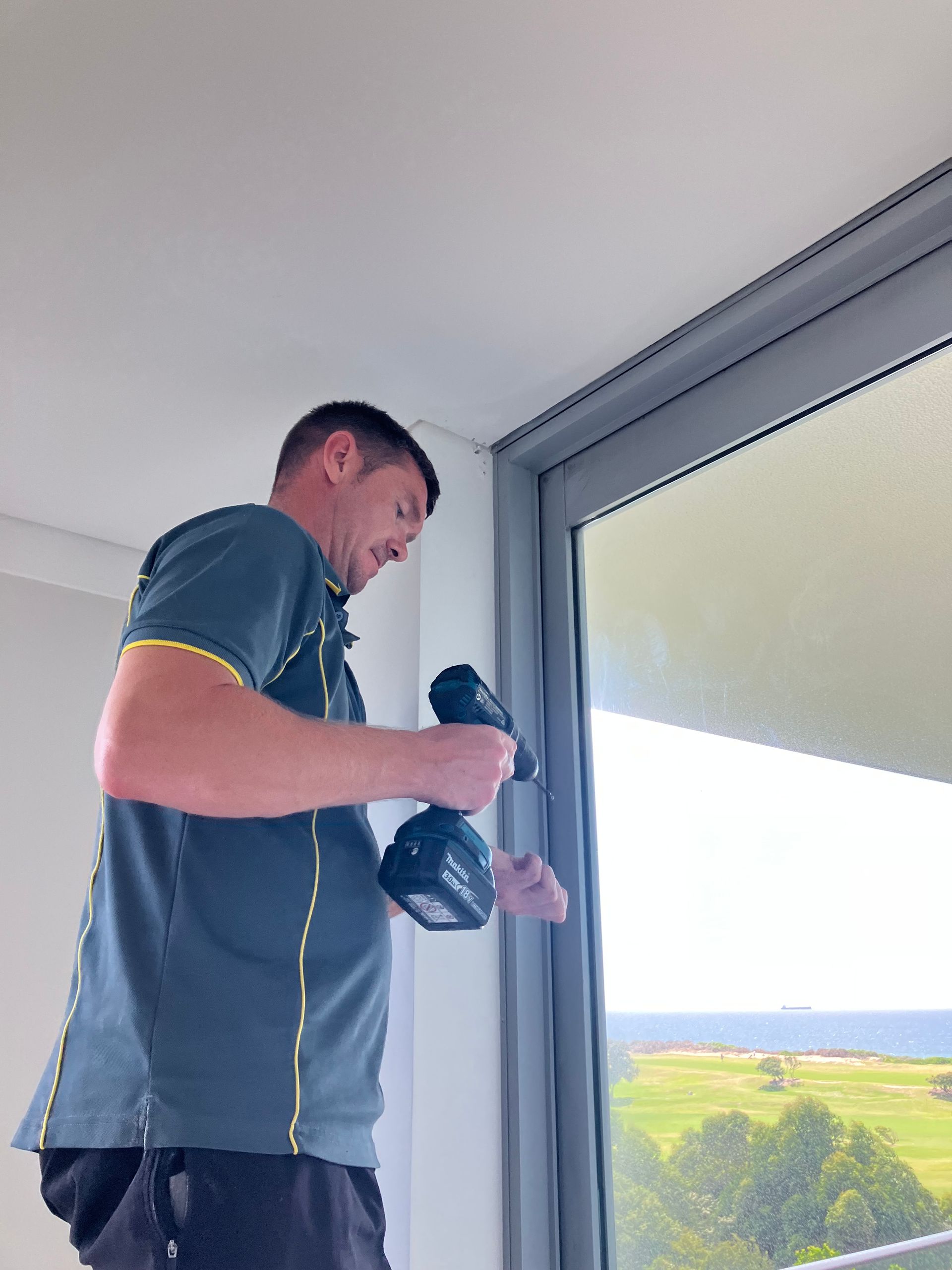 Man holding a camera by a window with a bright landscape outside