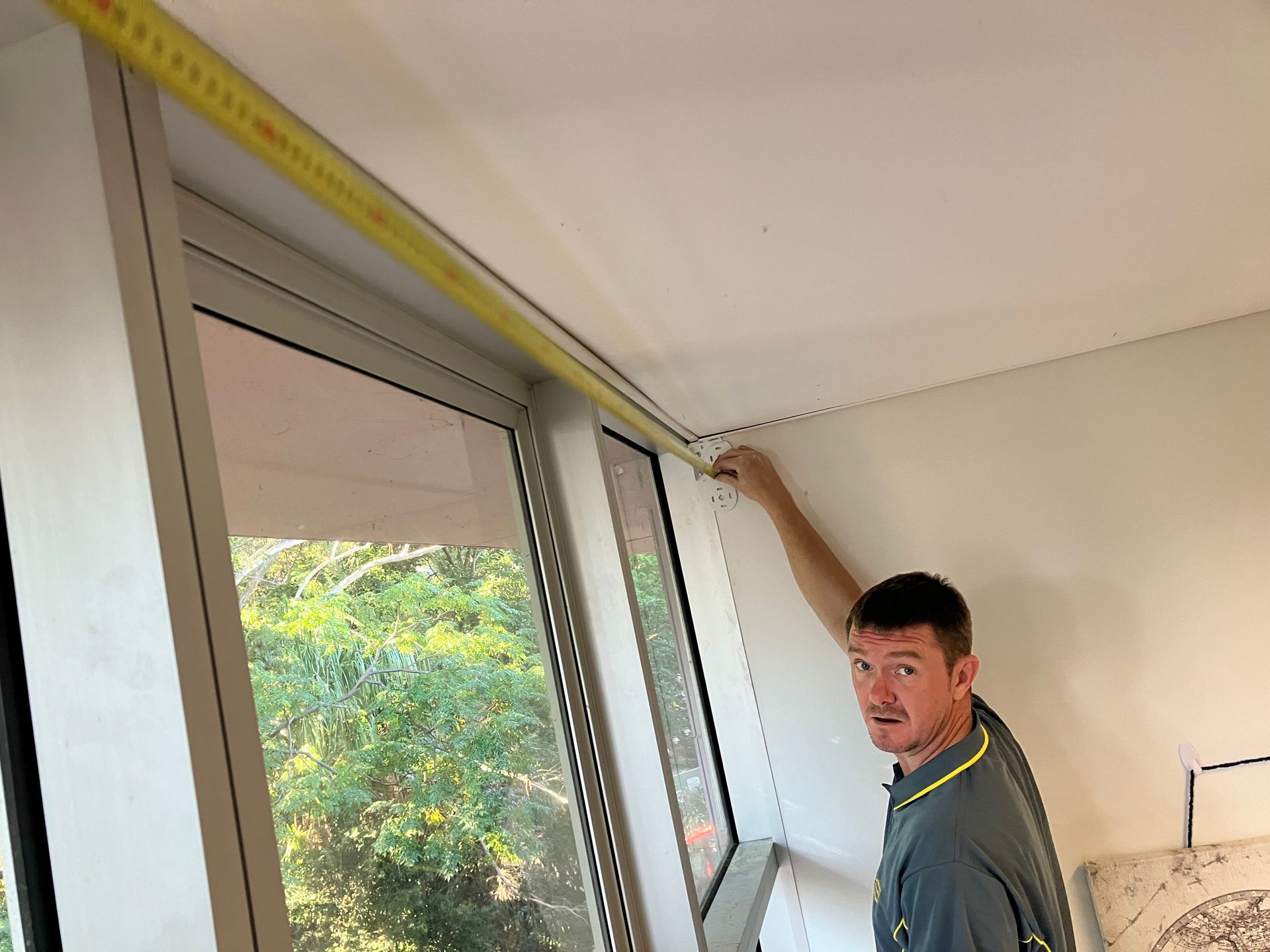 Person measuring a window frame with a tape measure in a room under renovation