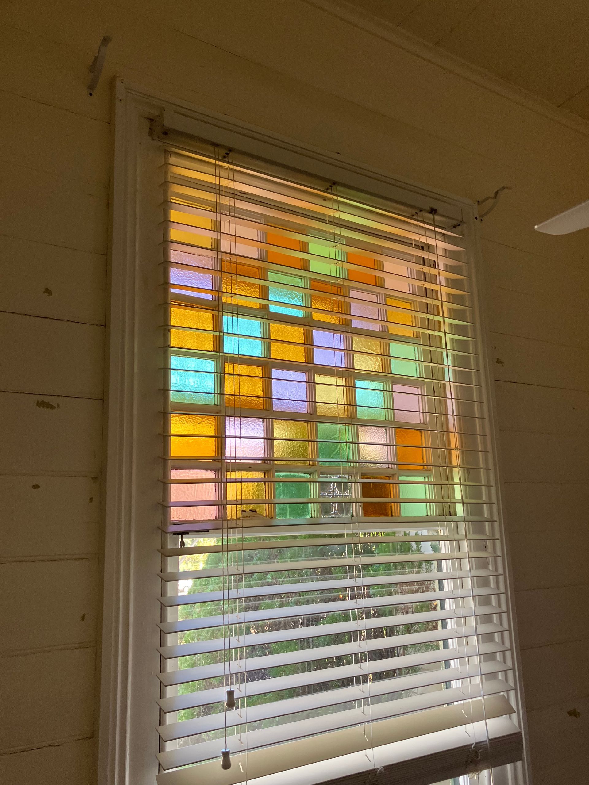Colorful sticky notes covering a window with white blinds in a room