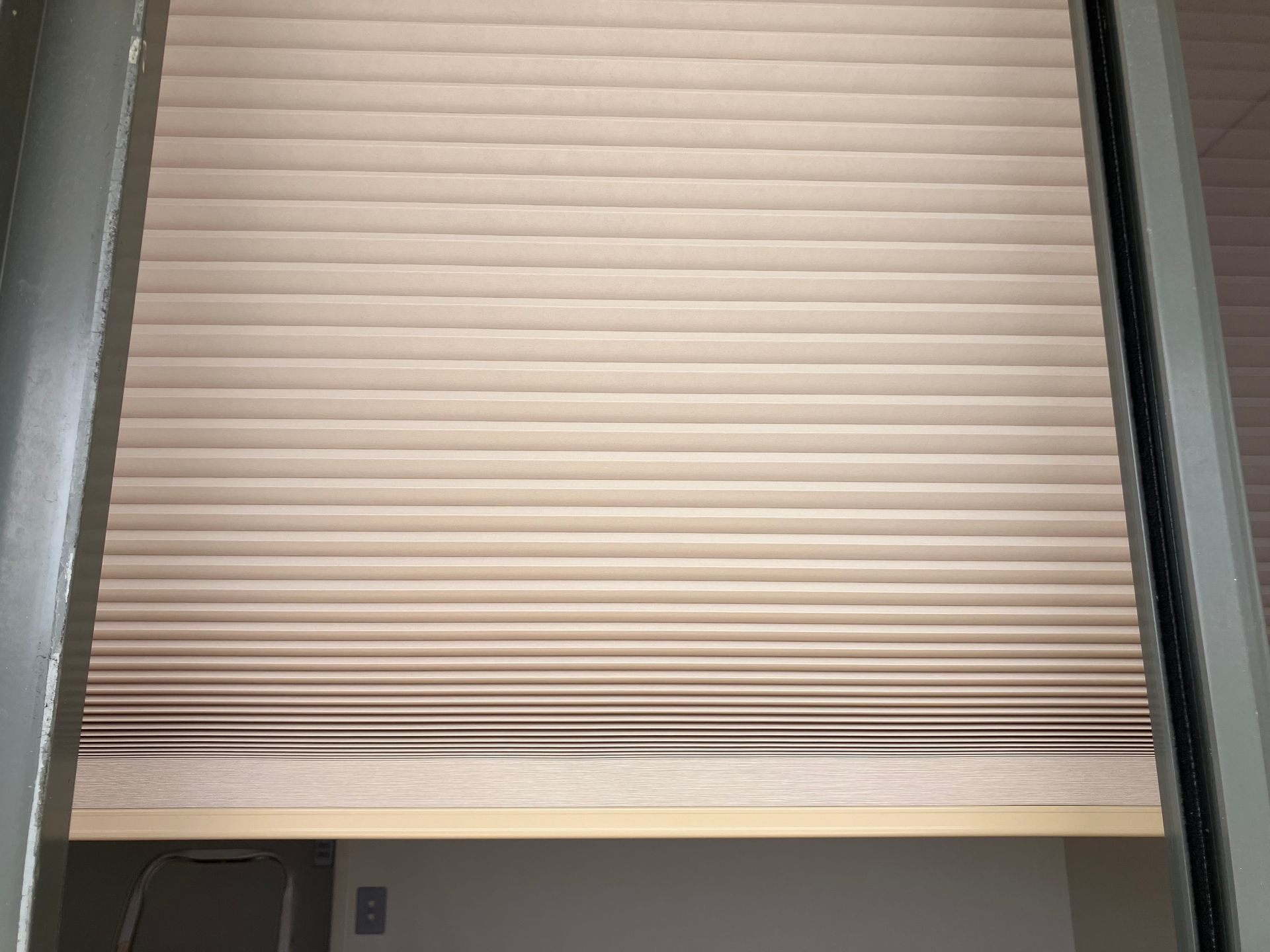 Closed beige Verishade blind framed by dark trim, with a small gap at the bottom.