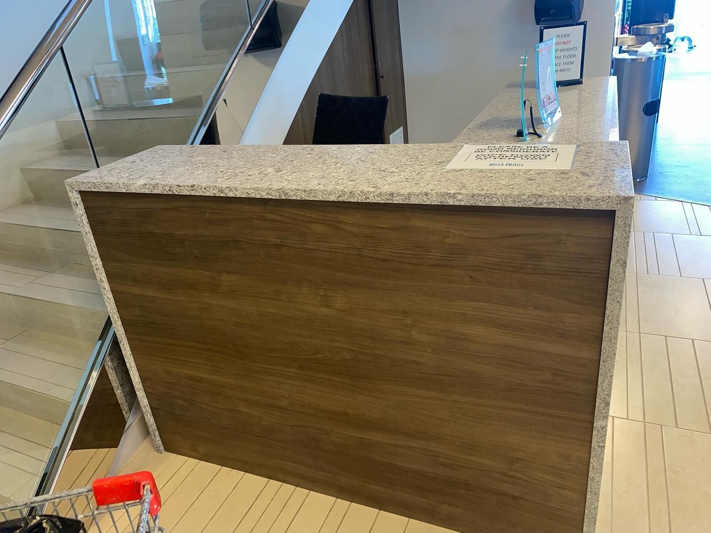 A reception desk with a granite top and wood front in a brightly lit hallway.