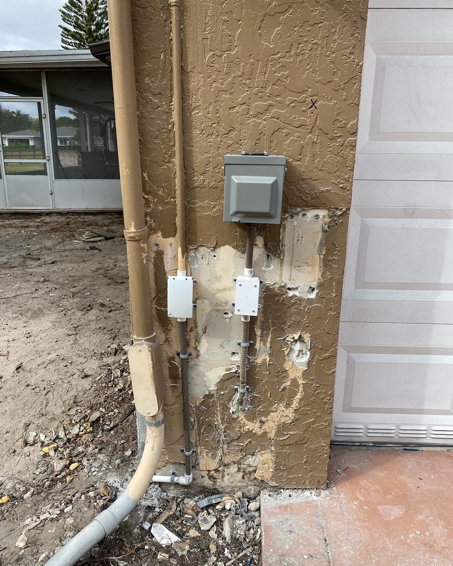 Electrical components on an exterior stucco wall: conduit, boxes, and wiring.