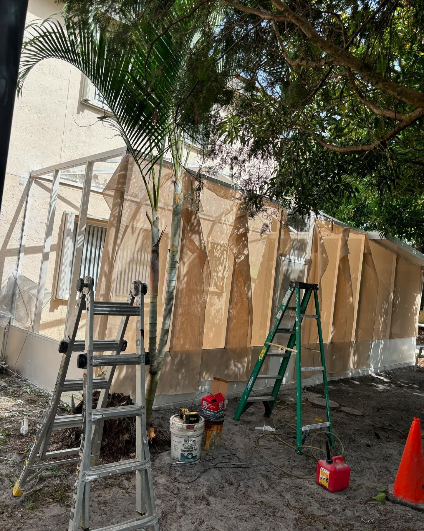 Construction site with partially built wall, ladders, tools, and trees.