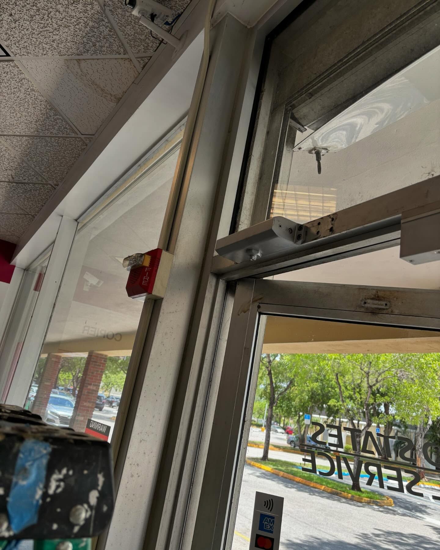 A door with an automatic opener and a sign for United States Postal Service. Outside is a street view.