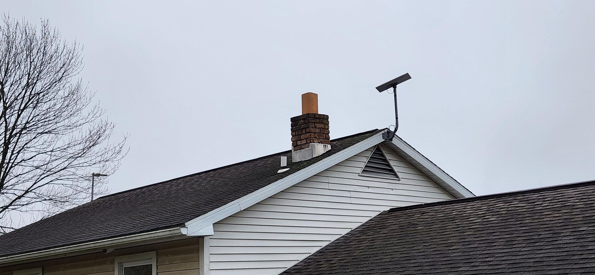 House roof with TV antenna and chimney under an overcast sky