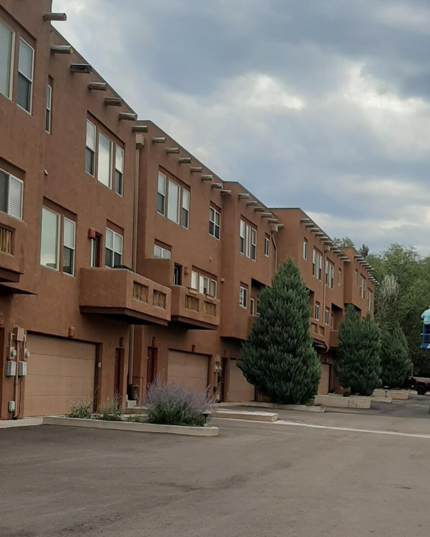 Brown apartment buildings lining an empty parking lot under a cloudy sky