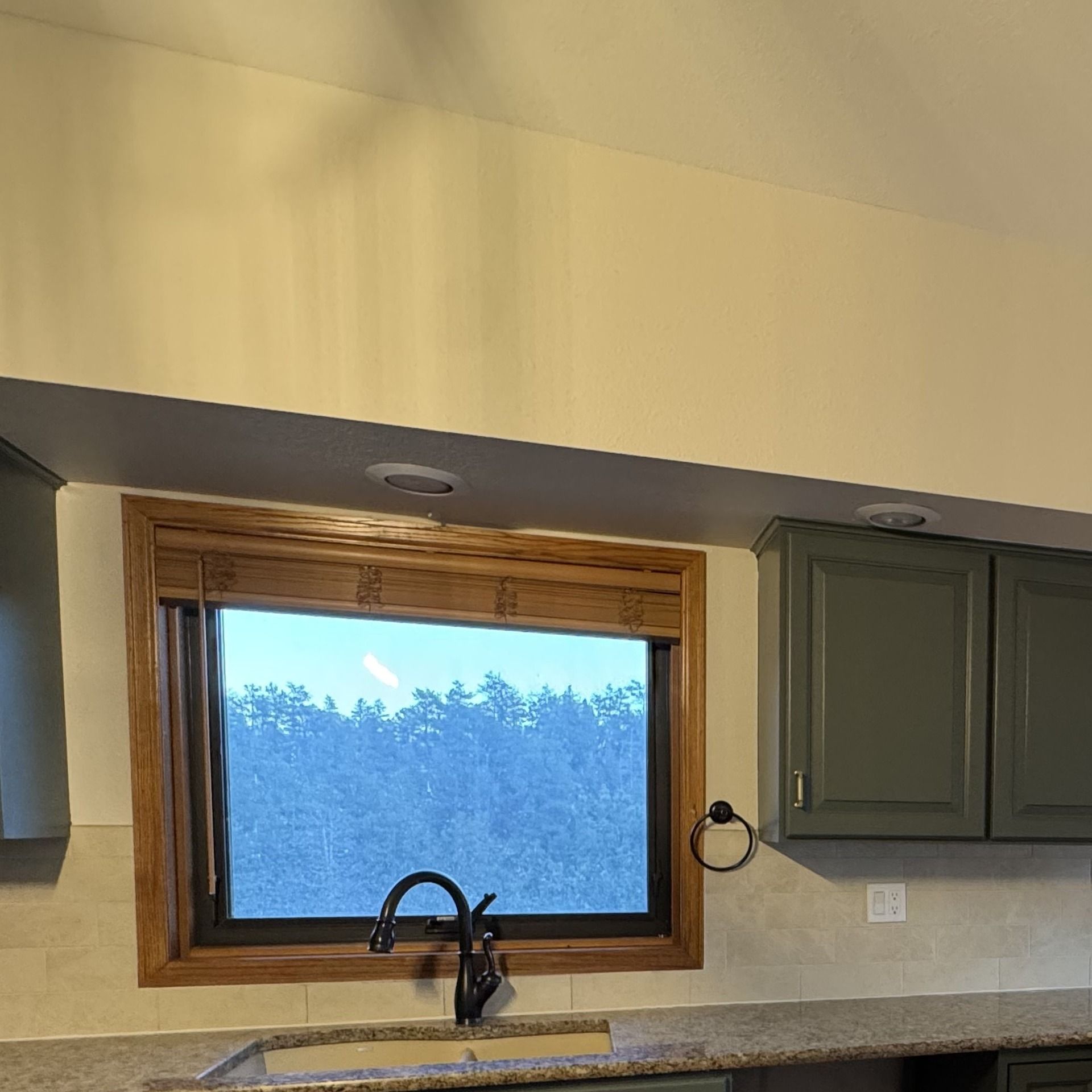 Sage kitchen cabinets along window wall