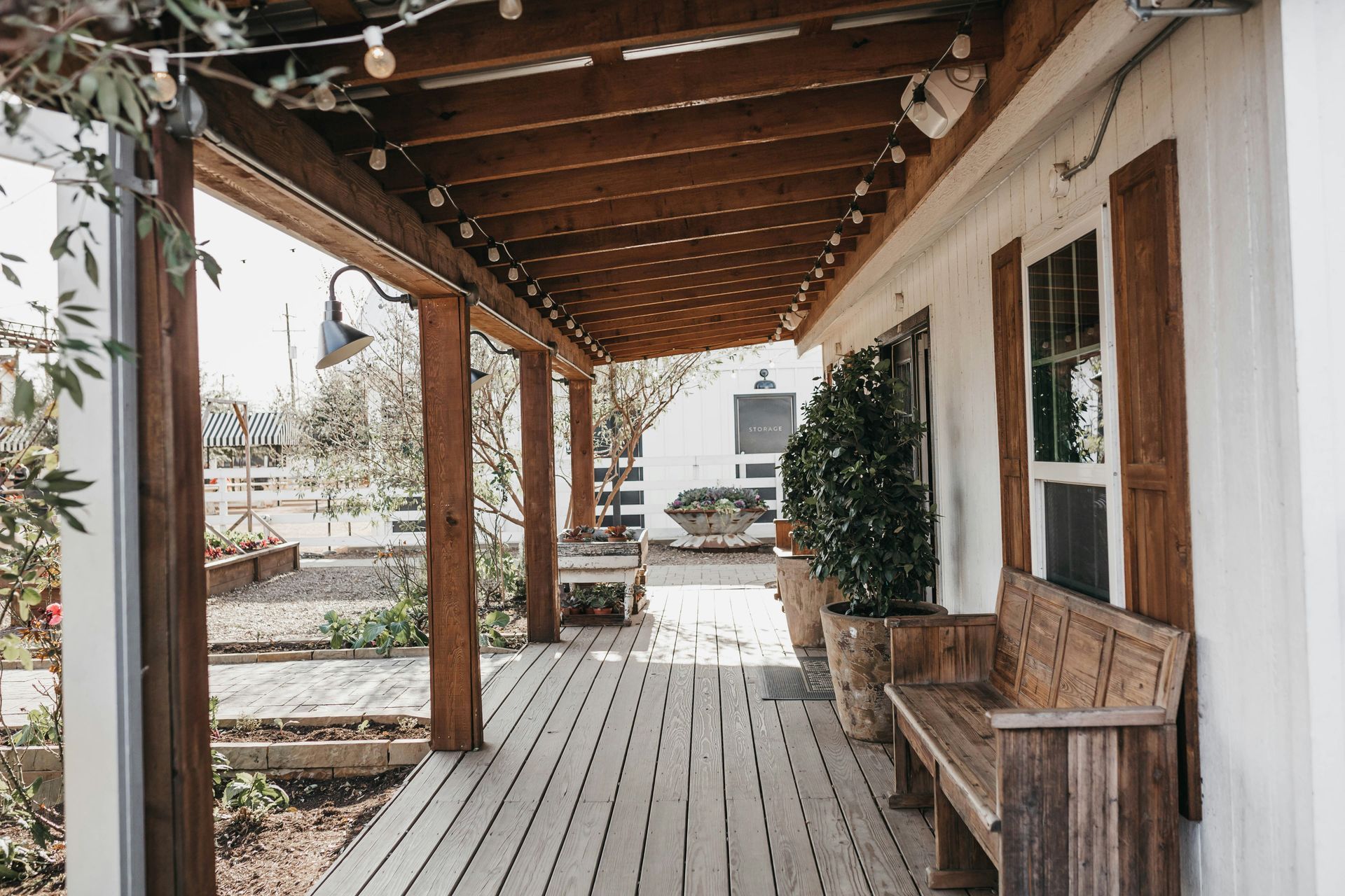 Covered wooden porch with bench, string lights, and snow-covered yard beyond