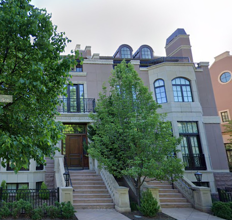 Elegant townhouse facade with front steps, large windows, and trees lining the entrance