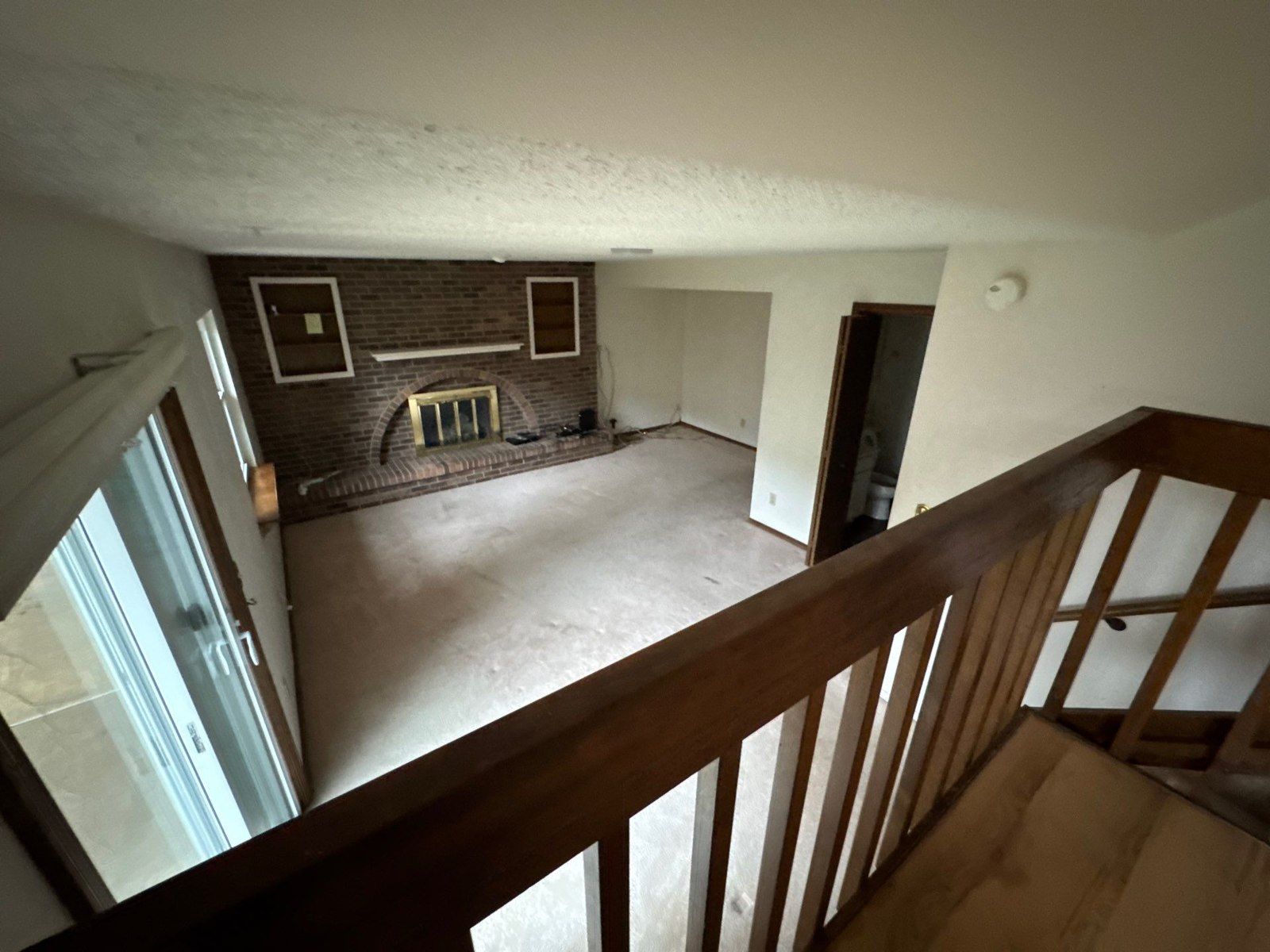 Den walls and ceiling beside a brick fireplace and wood railing in a Colorado Springs interior estimate