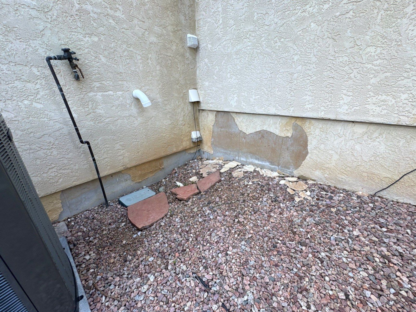 Lower stucco wall with an exposed patch and landscaping at the project