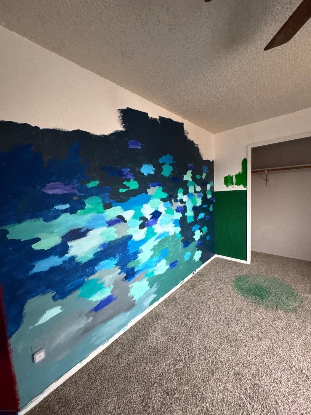Blue and green artwork across an existing bedroom wall before the proposed repaint
