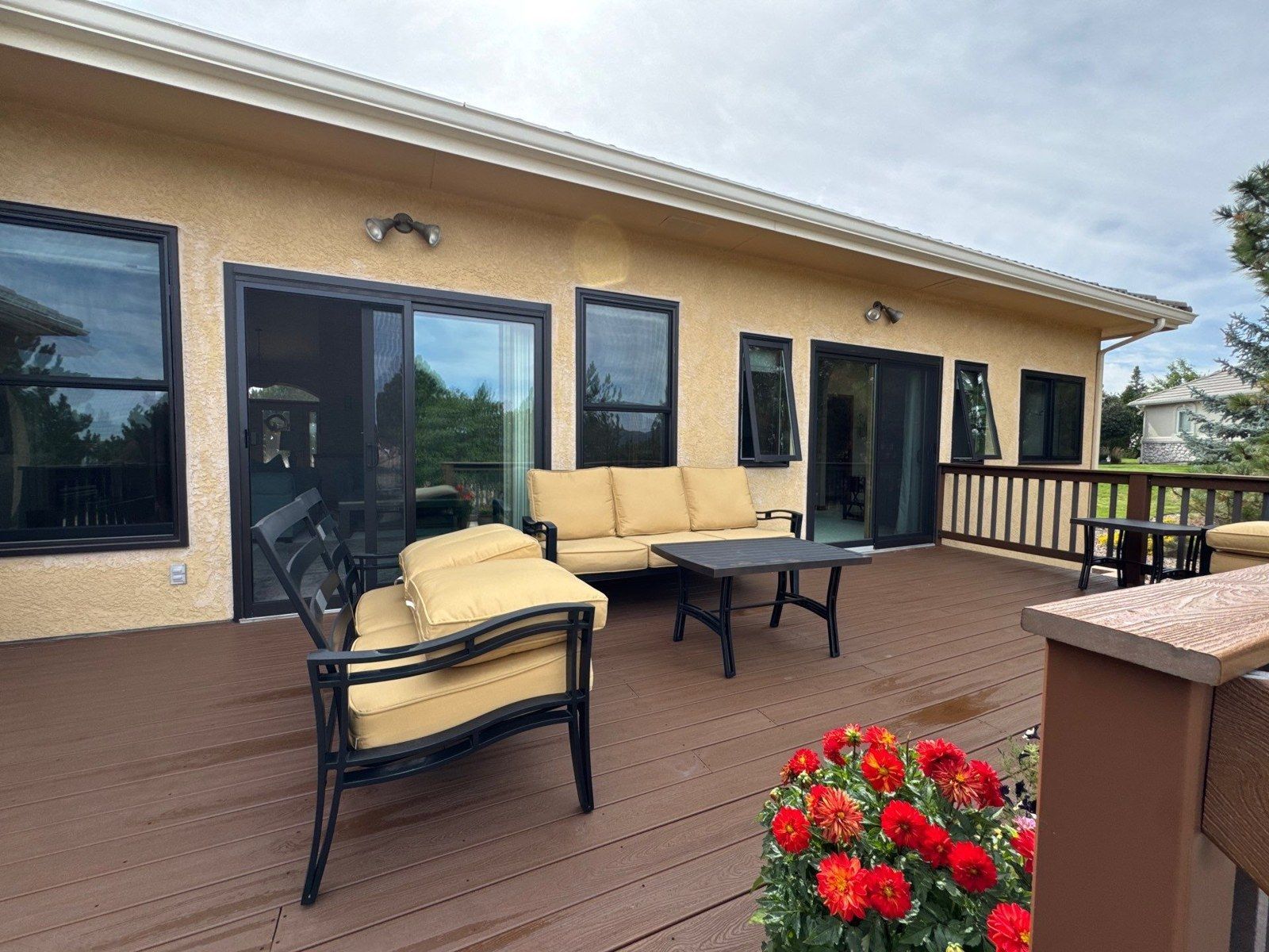 Outside view of the same deck doors beside stucco walls, windows and existing deck furnishings
