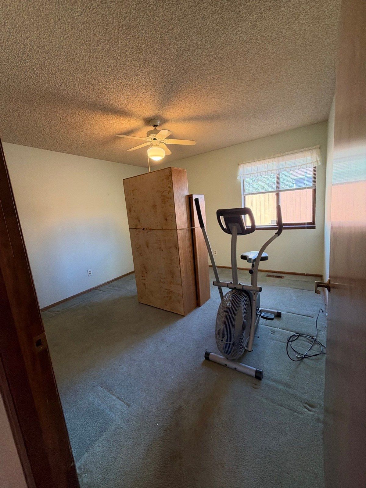 Bedroom containing exercise equipment and a cabinet beneath a textured ceiling at the same property