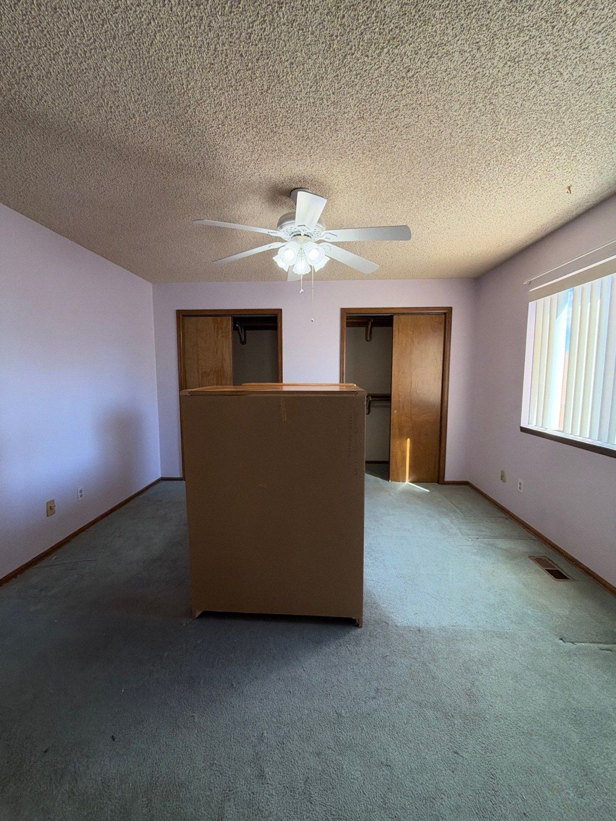 Second bedroom view showing wall surfaces, a ceiling fan, wood closet doors and existing carpet
